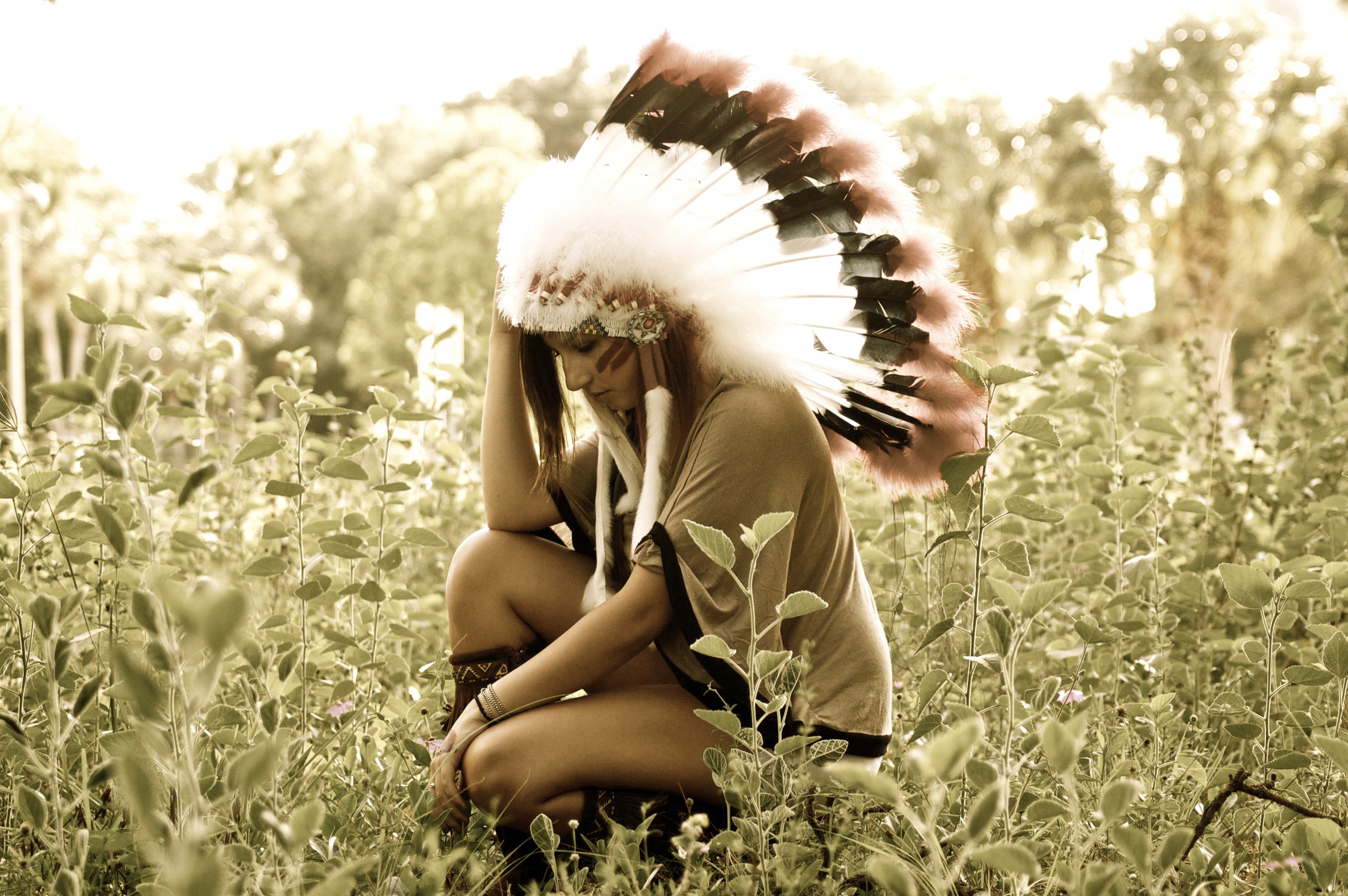 Woman wearing a Native American headdress in a field HD Wallpaper