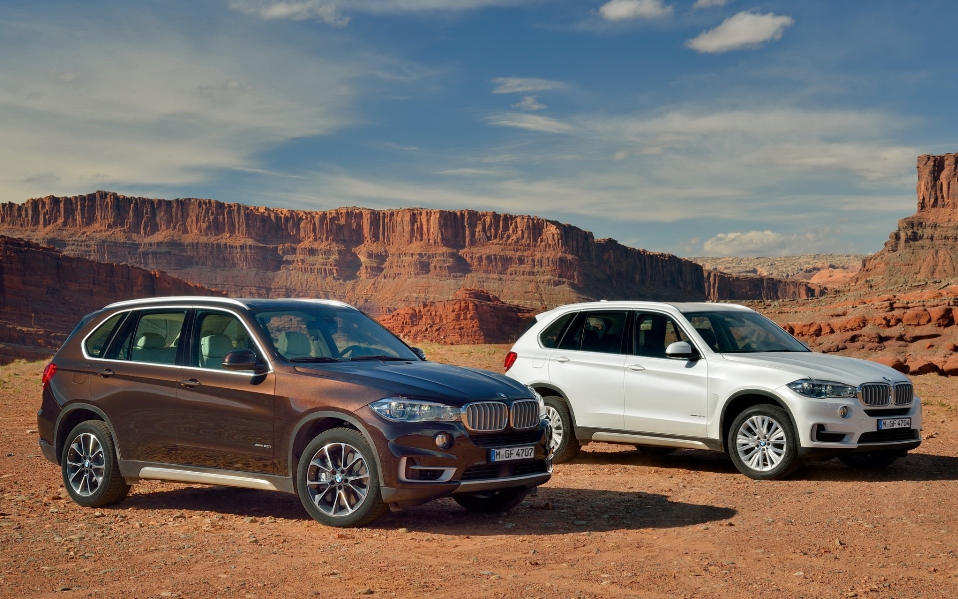 Two BMW X5 SUVs in a desert canyon HD Wallpaper