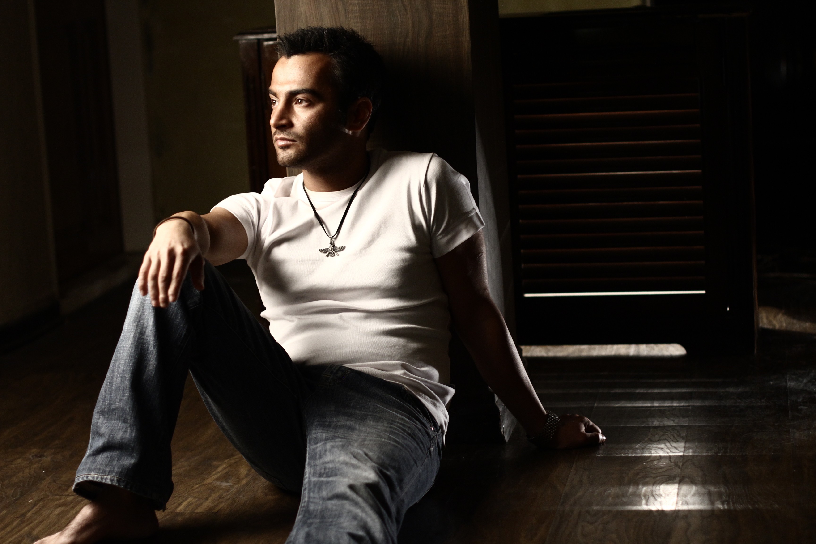 Man in white t-shirt and jeans sitting on floor HD Wallpaper
