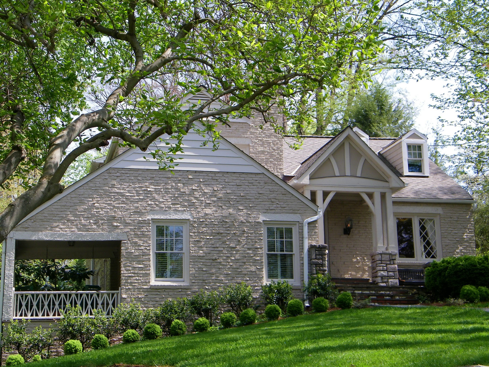 Stone house with porch and manicured lawn HD Wallpaper