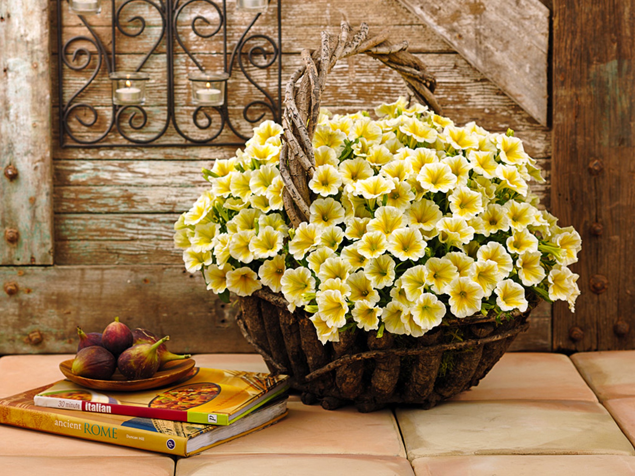 Yellow petunias in a basket with figs and books HD Wallpaper