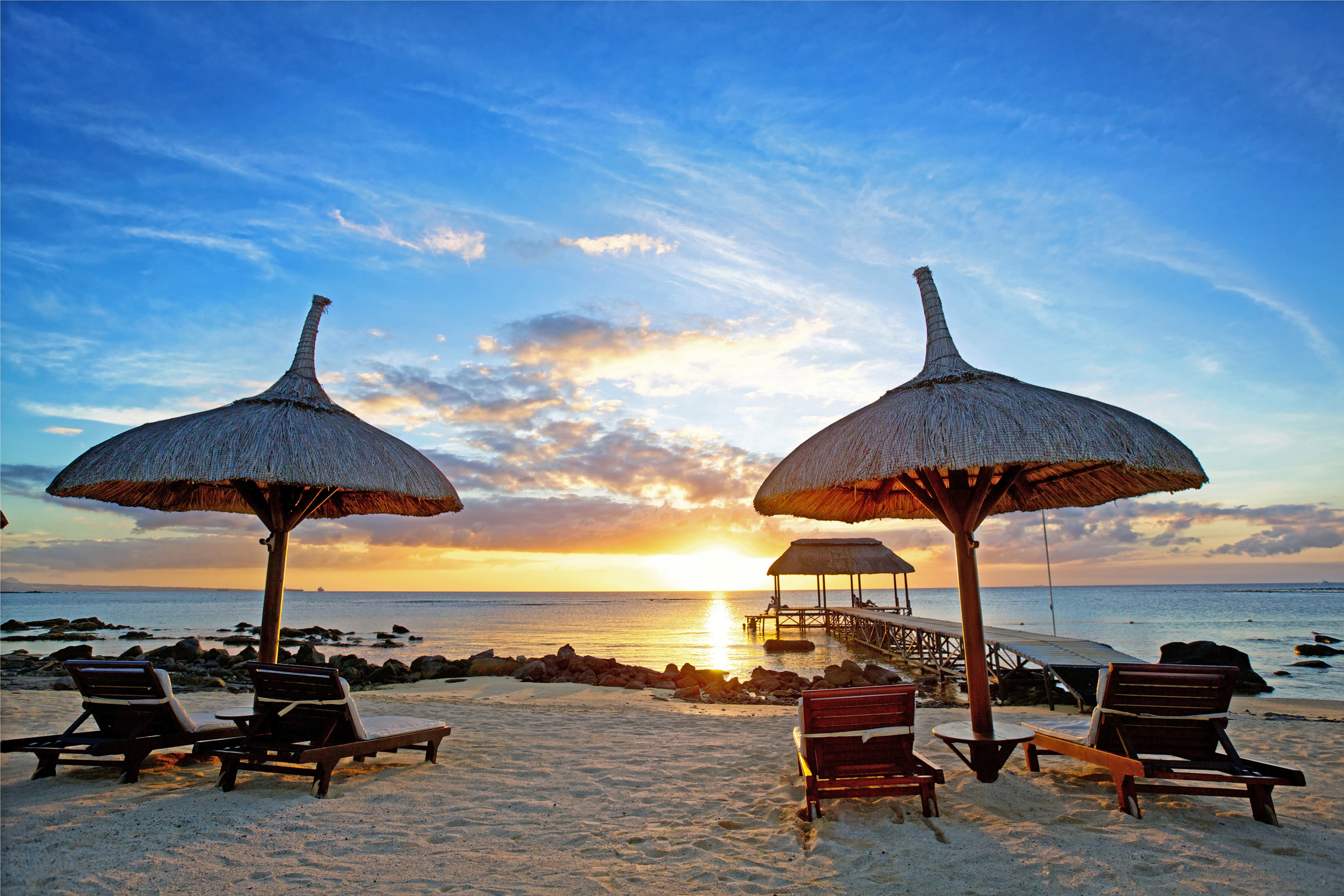 Beach with lounge chairs and umbrellas at sunset HD Wallpaper