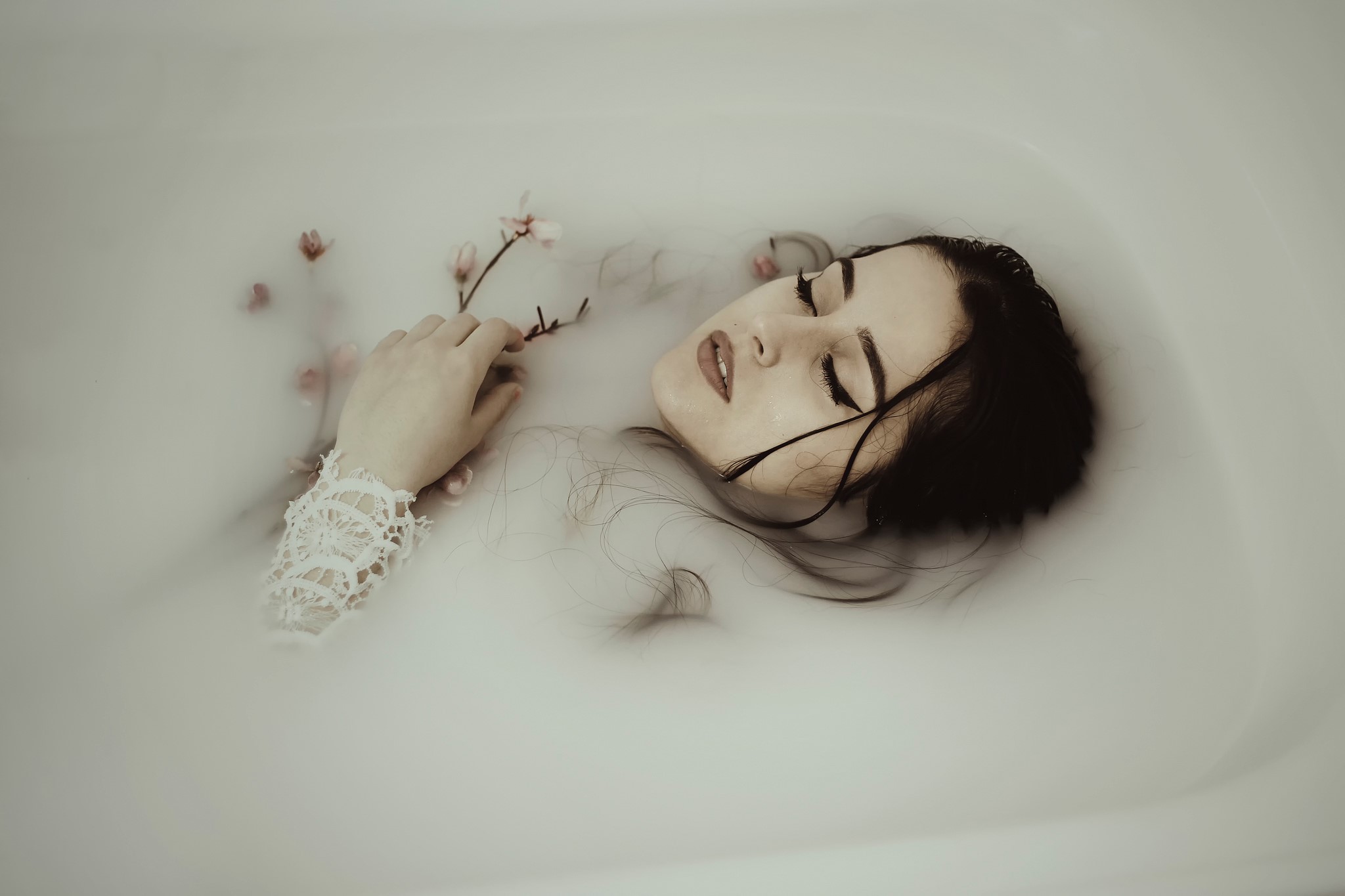 Woman lying in a milk bath with flowers HD Wallpaper