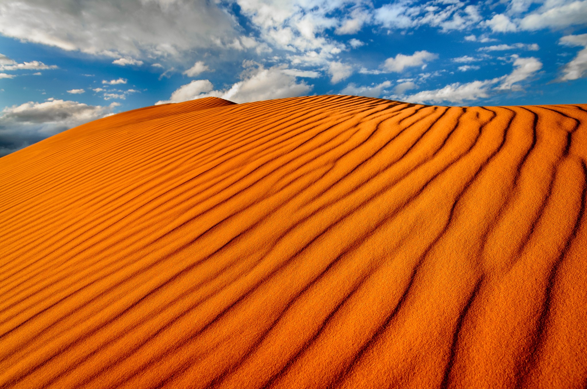 Orange sand dunes under a blue sky with clouds HD Wallpaper