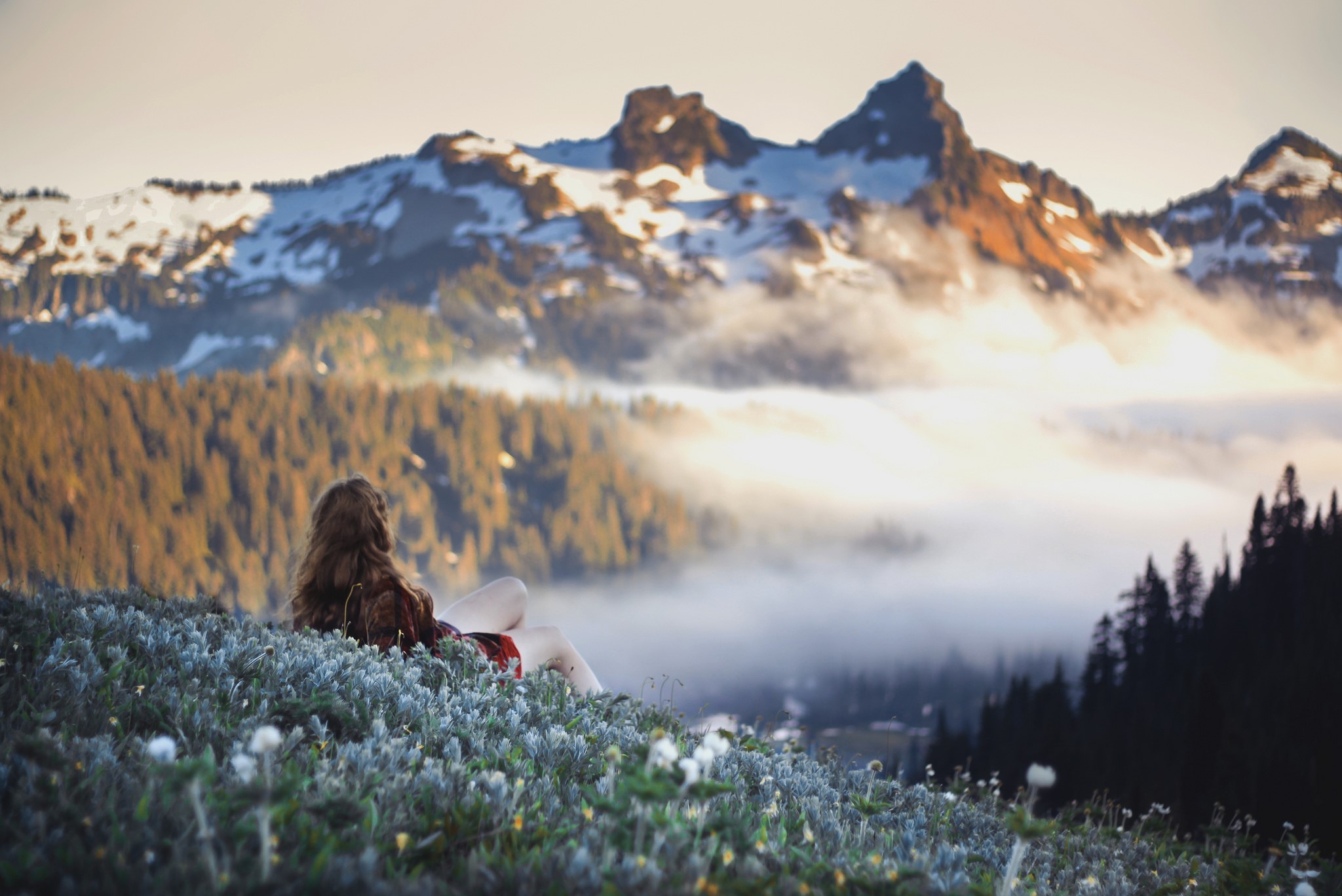 Woman sitting on a mountain overlooking fog and peaks HD Wallpaper