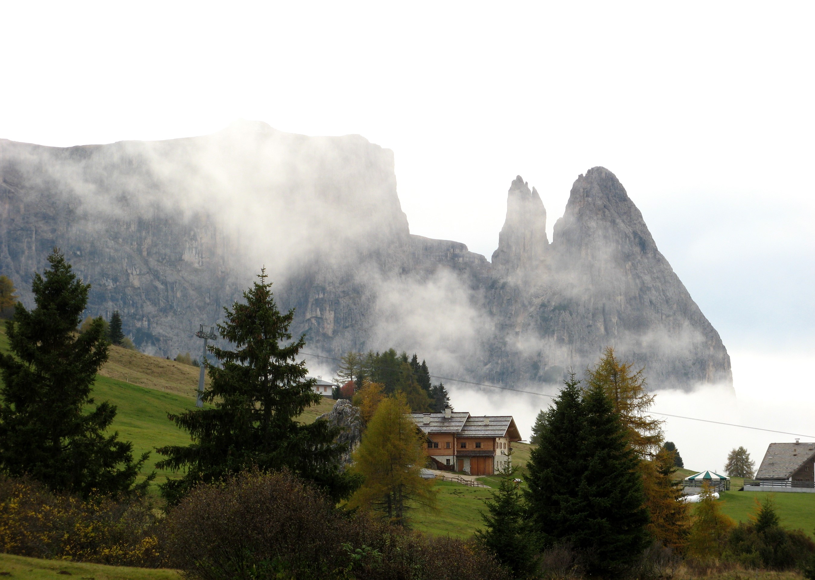 Mountain peaks shrouded in fog with houses and trees in Italy HD Wallpaper