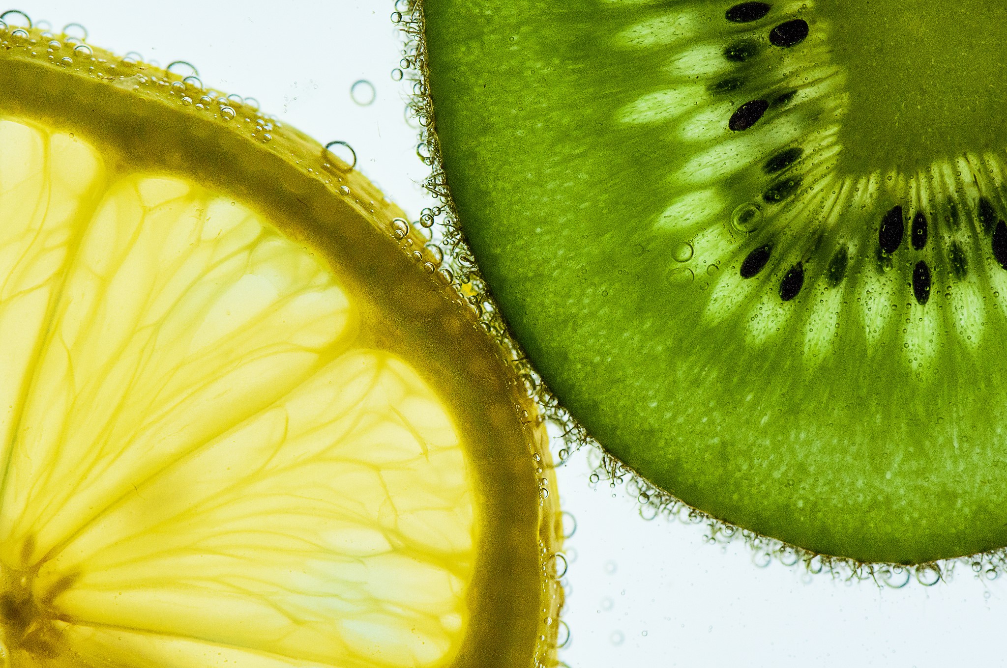 Close-up of lemon and kiwi slices in water with bubbles HD Wallpaper
