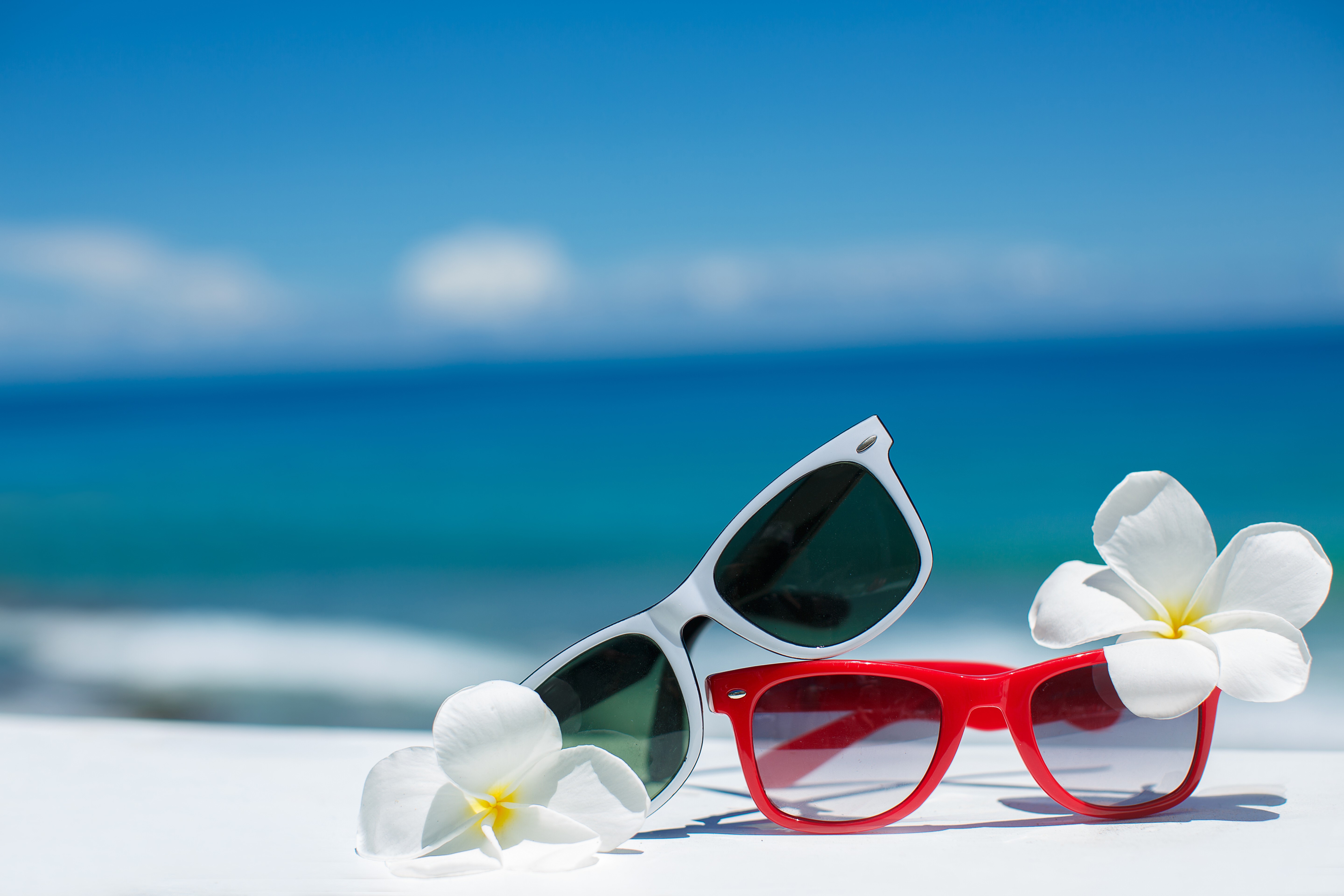 Two sunglasses and flowers on beach background HD Wallpaper