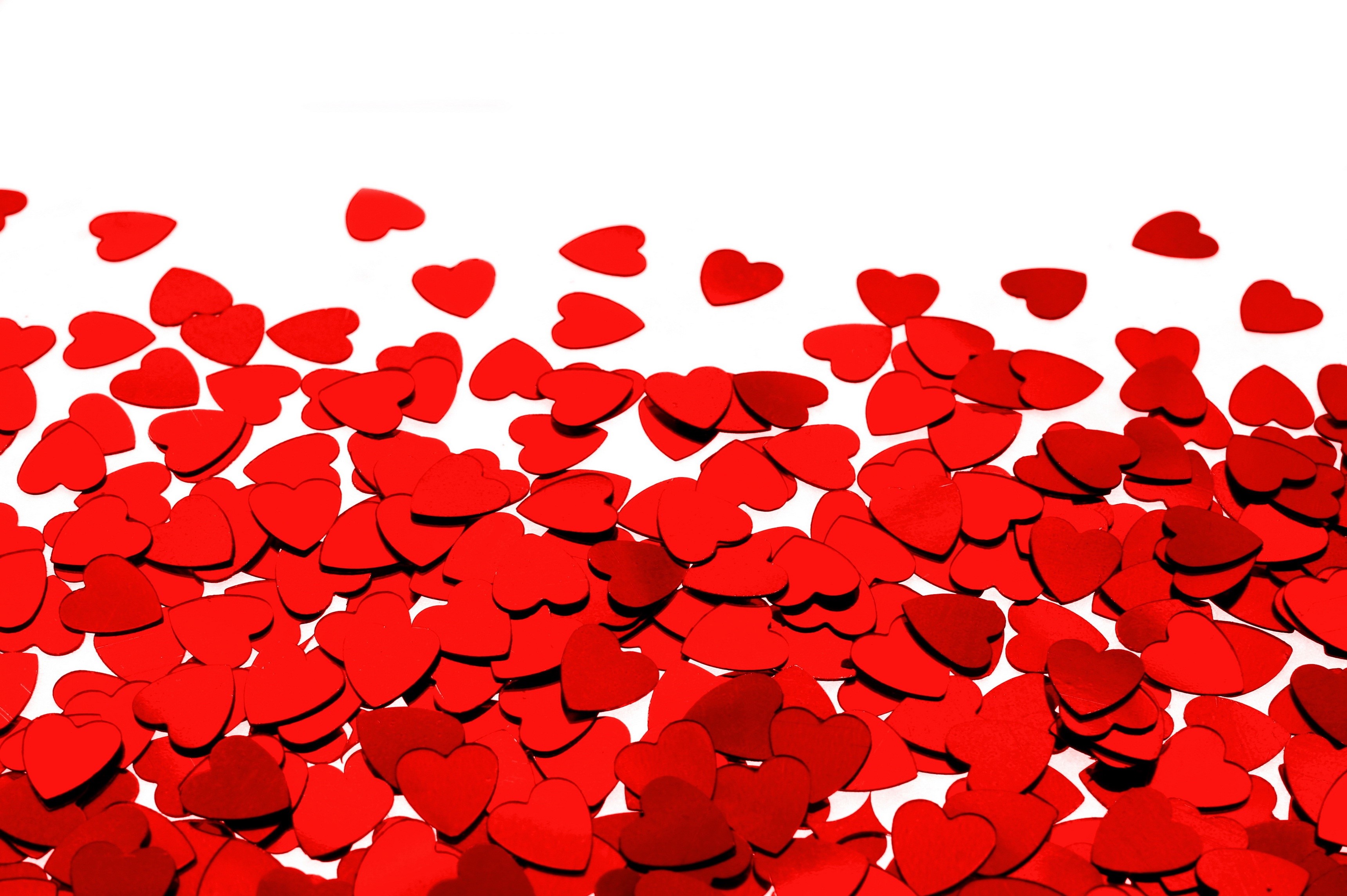 Scattered red heart confetti on a white background HD Wallpaper