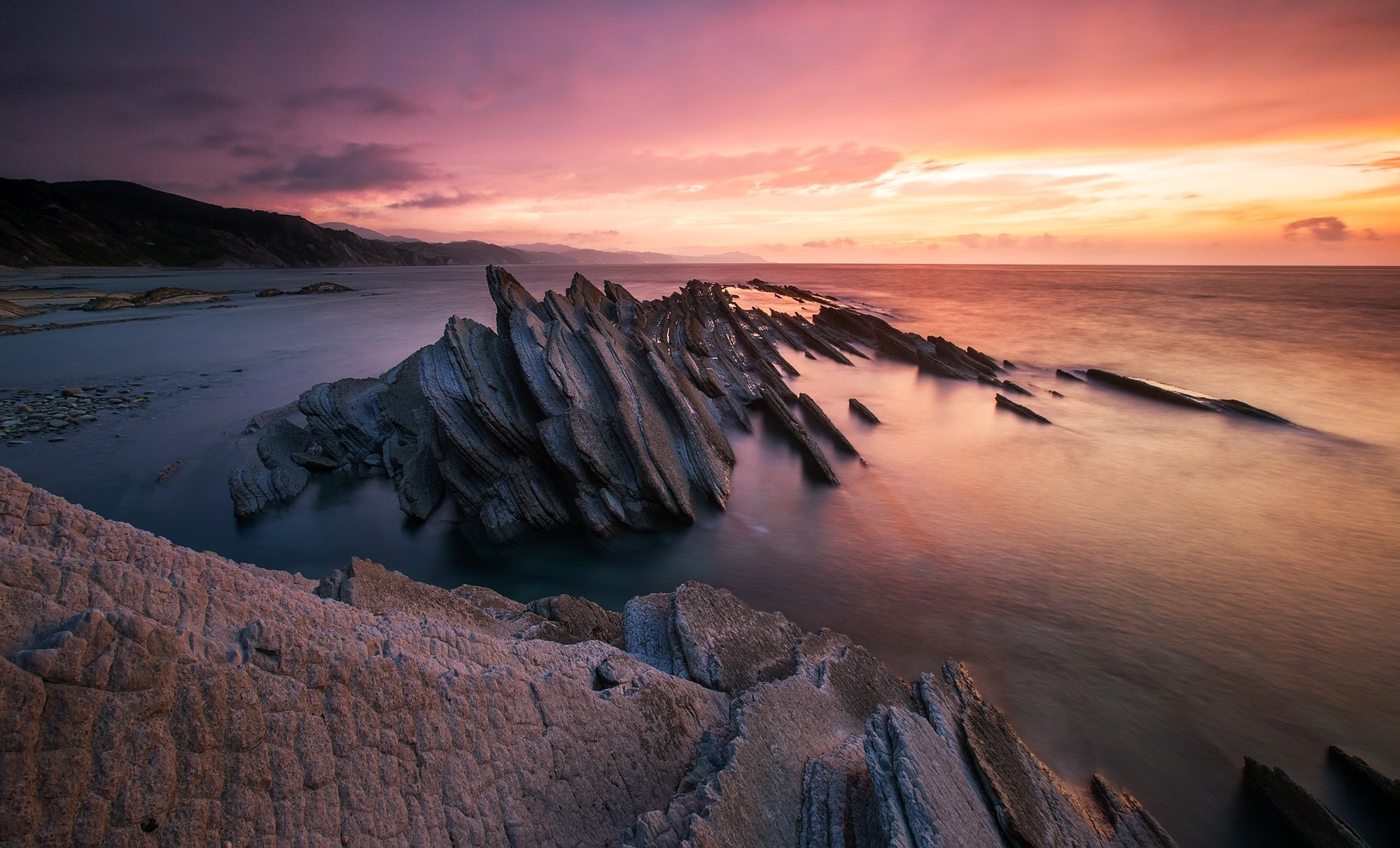 Jagged rock formations in the sea at sunset HD Wallpaper