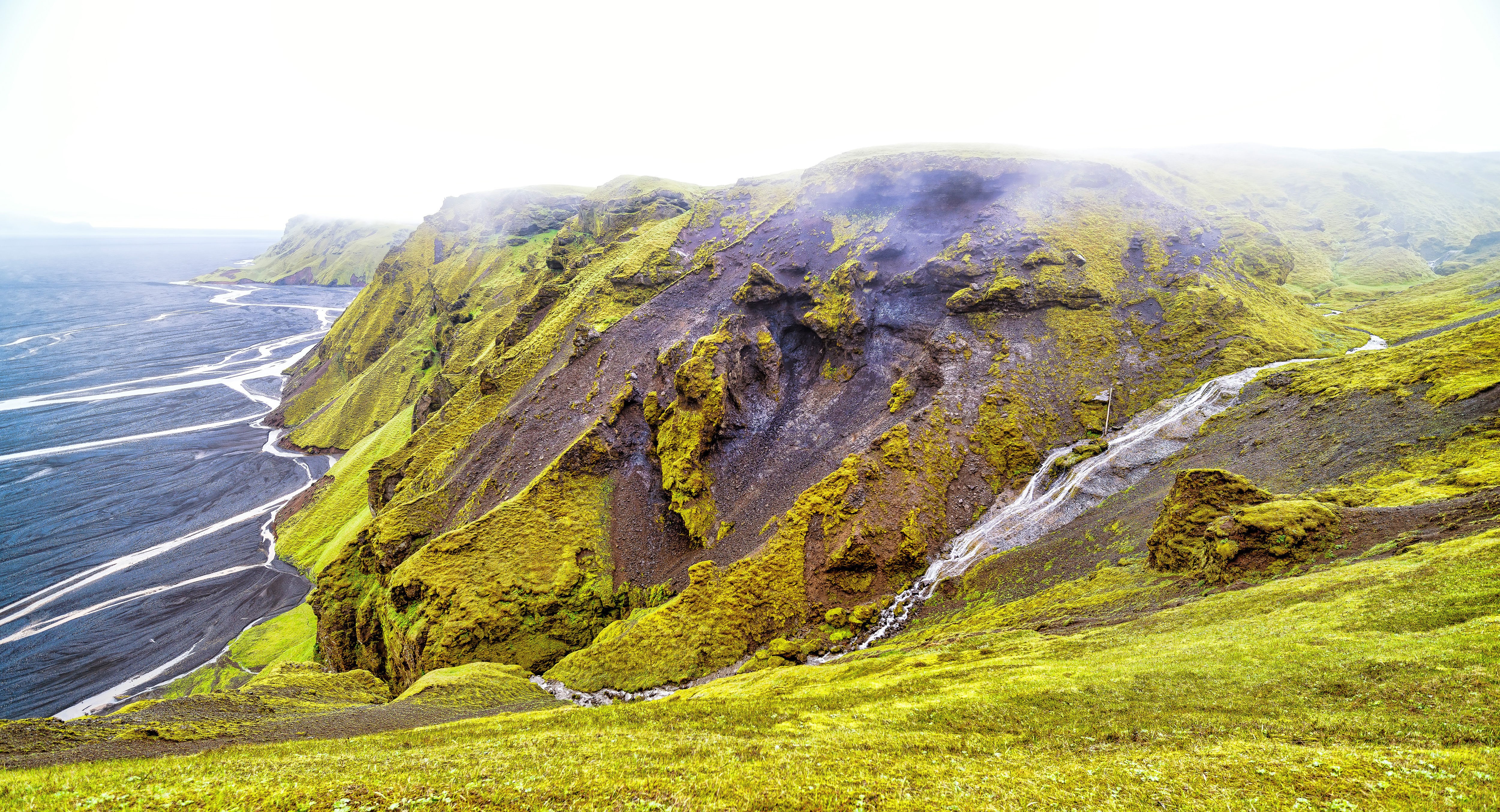 Mossy Cliffs Overlooking a Black Sand River Delta HD Wallpaper