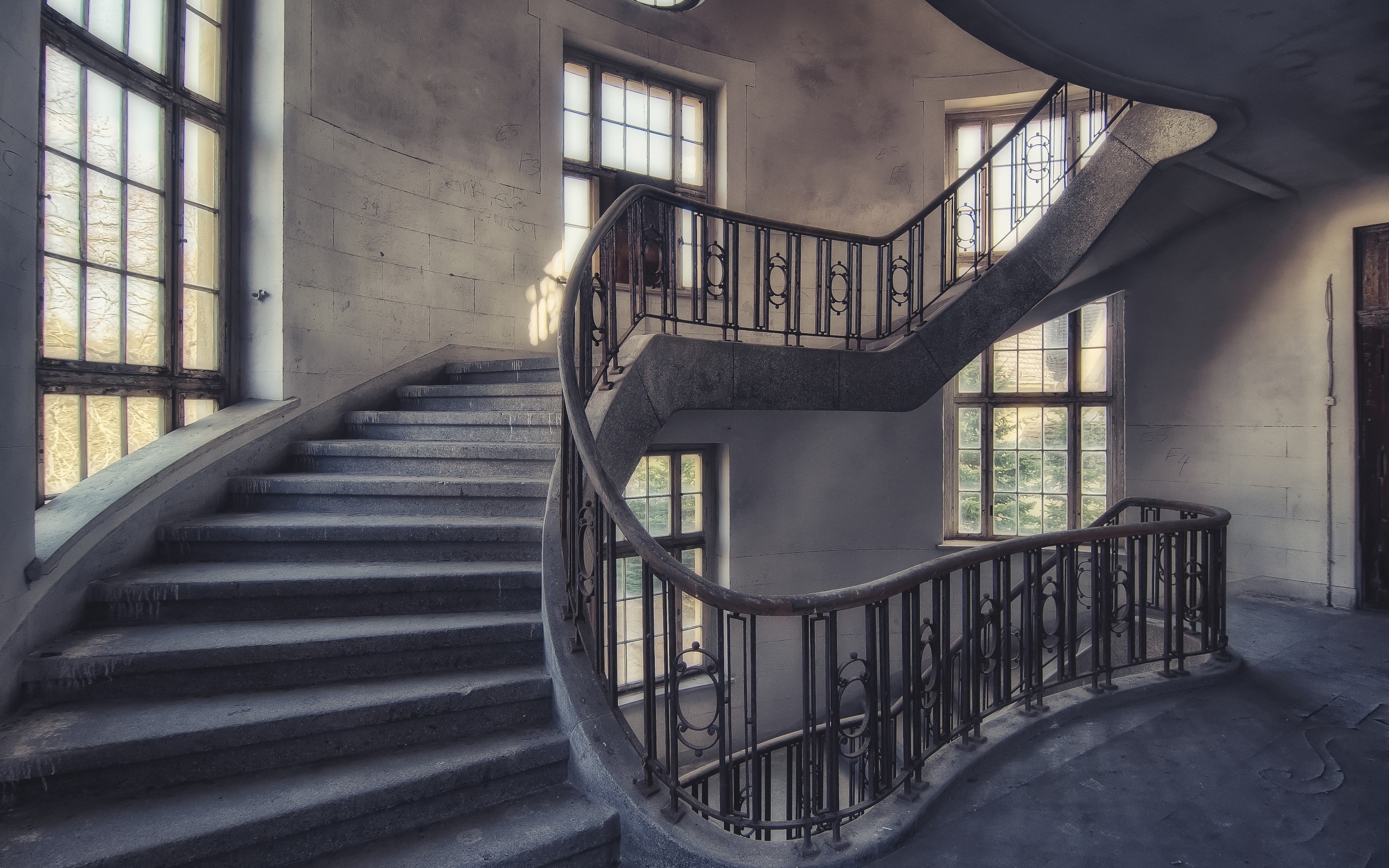 Abandoned building interior with spiral staircase and windows HD Wallpaper