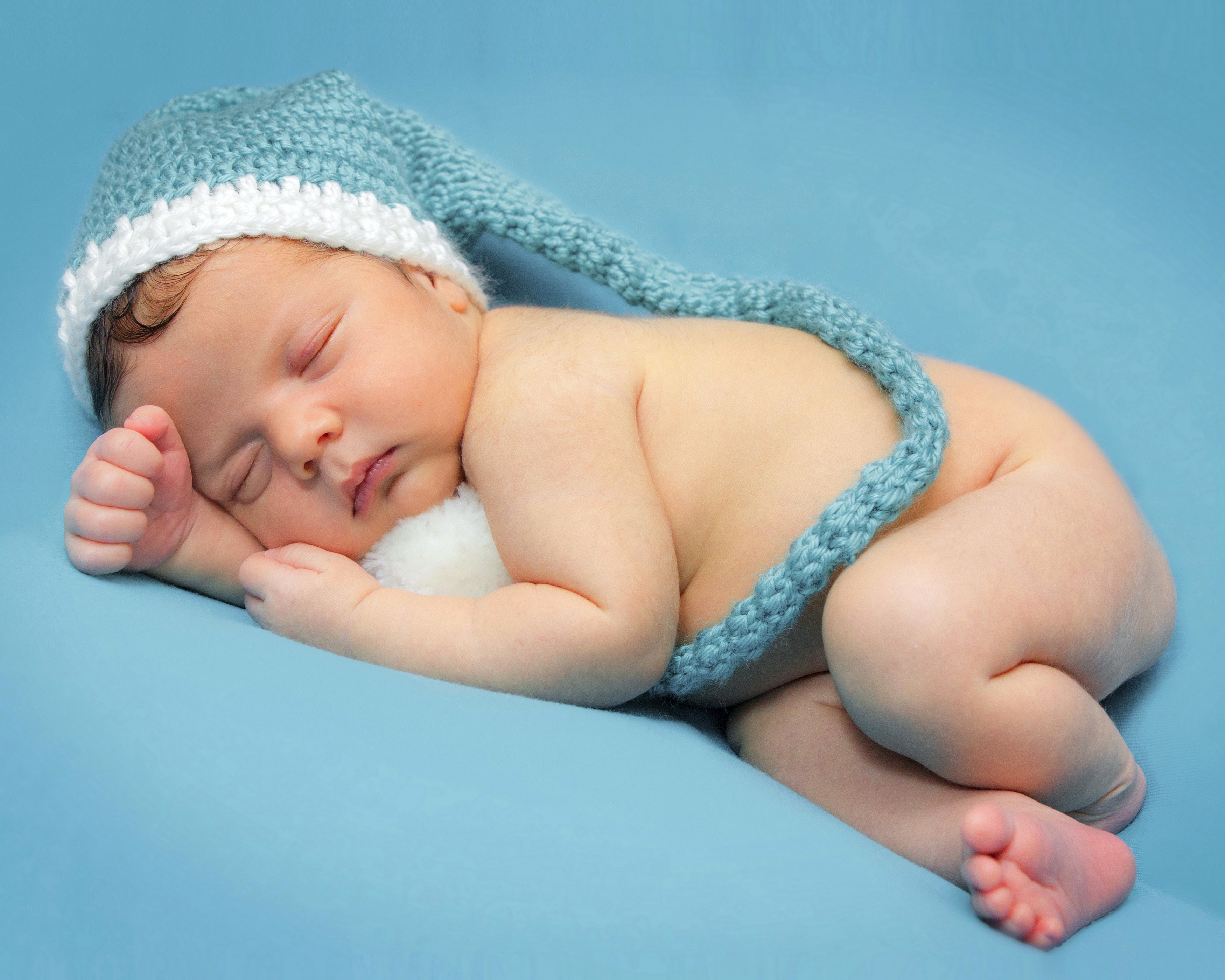 Newborn baby sleeping in a blue knitted hat HD Wallpaper
