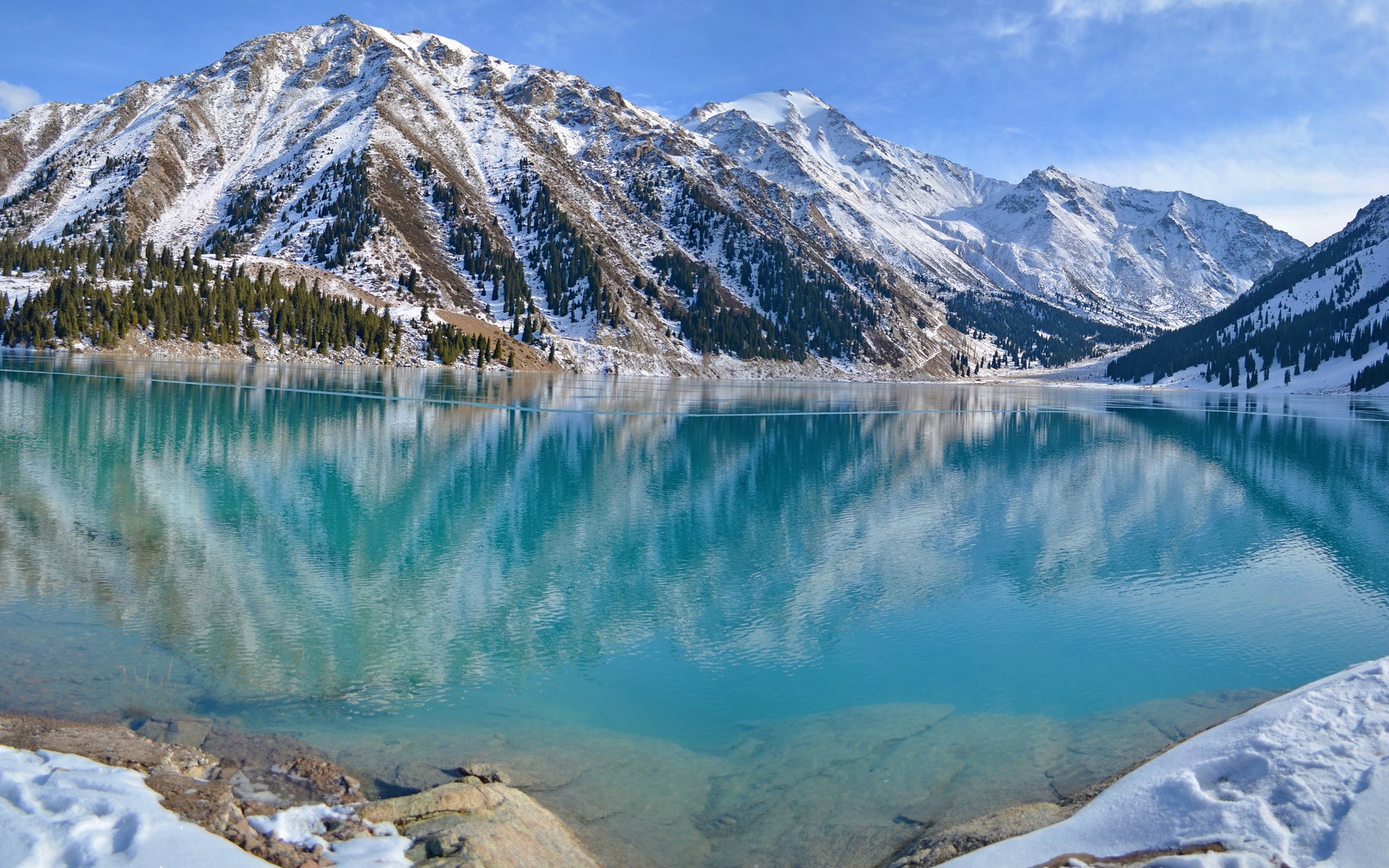 Turquoise mountain lake with snow-capped peaks and pine trees HD Wallpaper