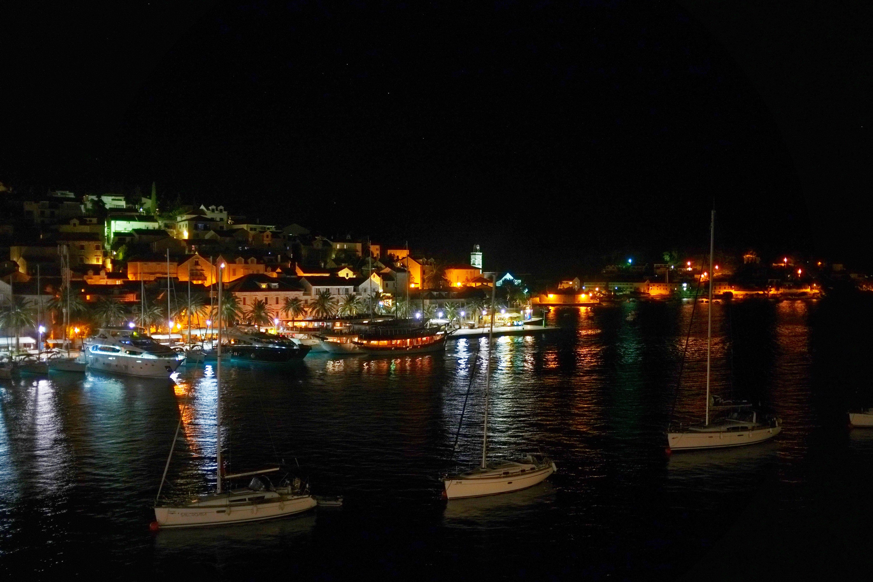 Night view of Hvar island marina with boats and illuminated houses HD Wallpaper
