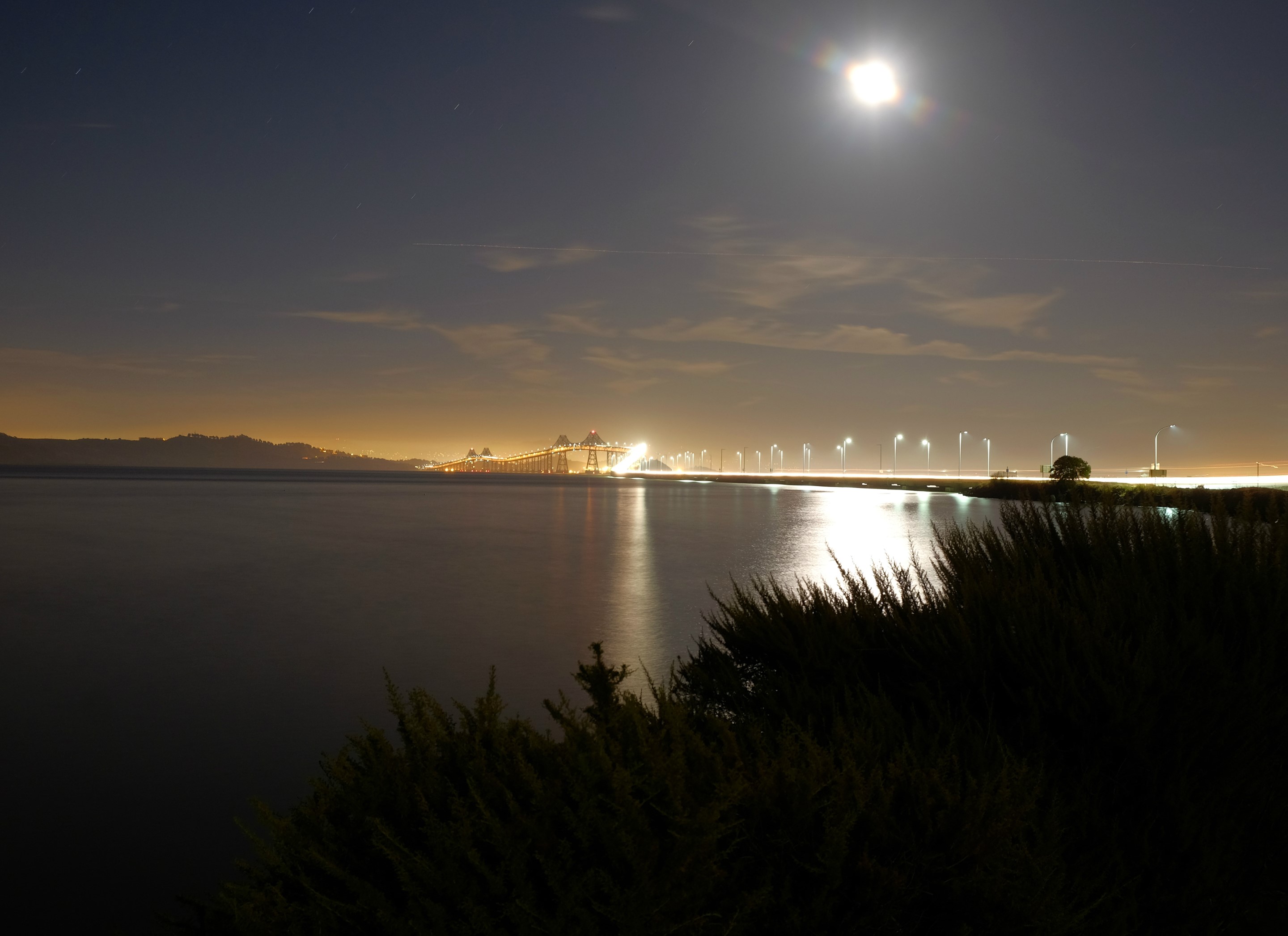 Night view of a bridge over a body of water with the moon in the sky HD Wallpaper
