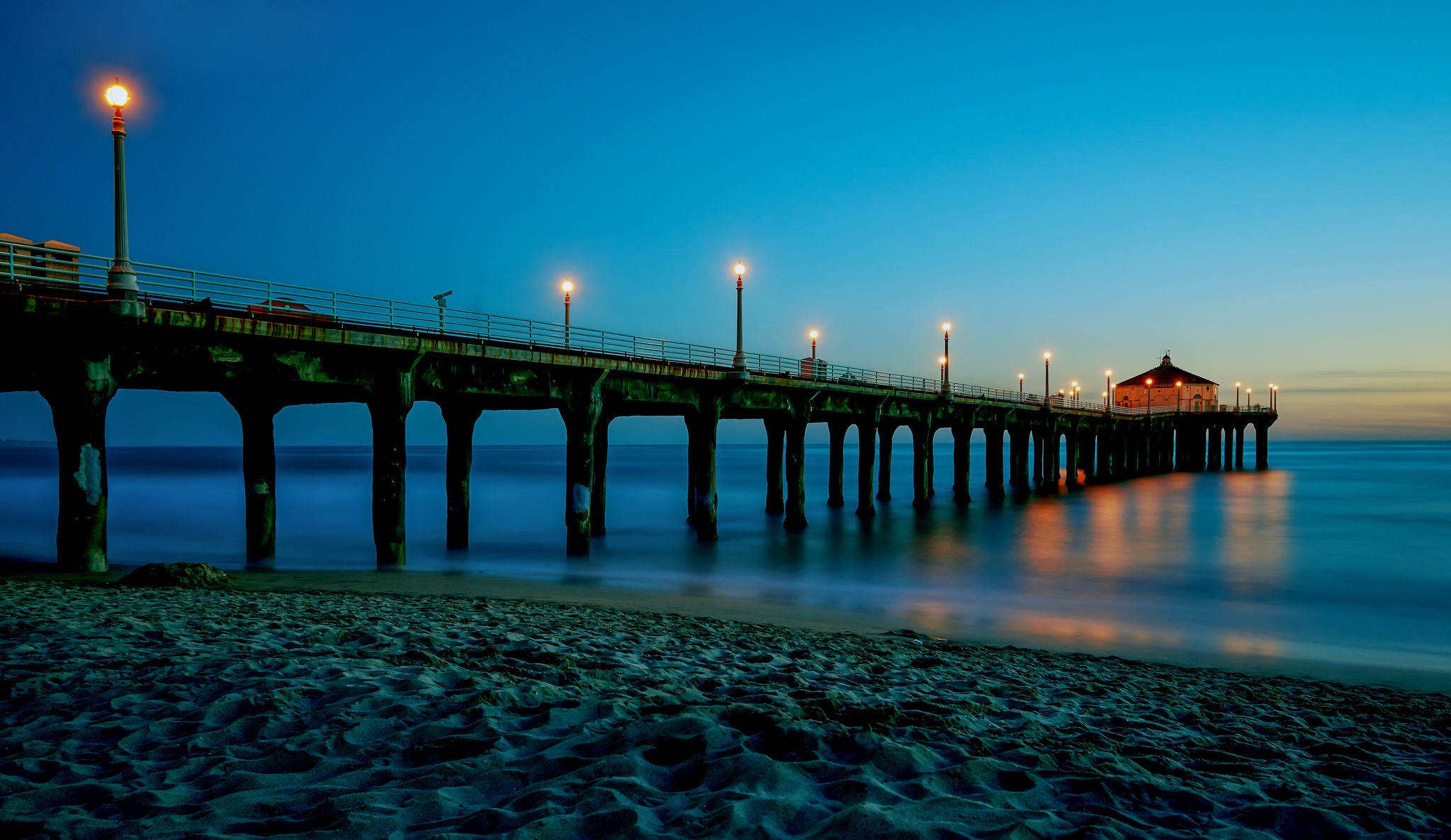 Pier with street lights over the ocean at dusk HD Wallpaper