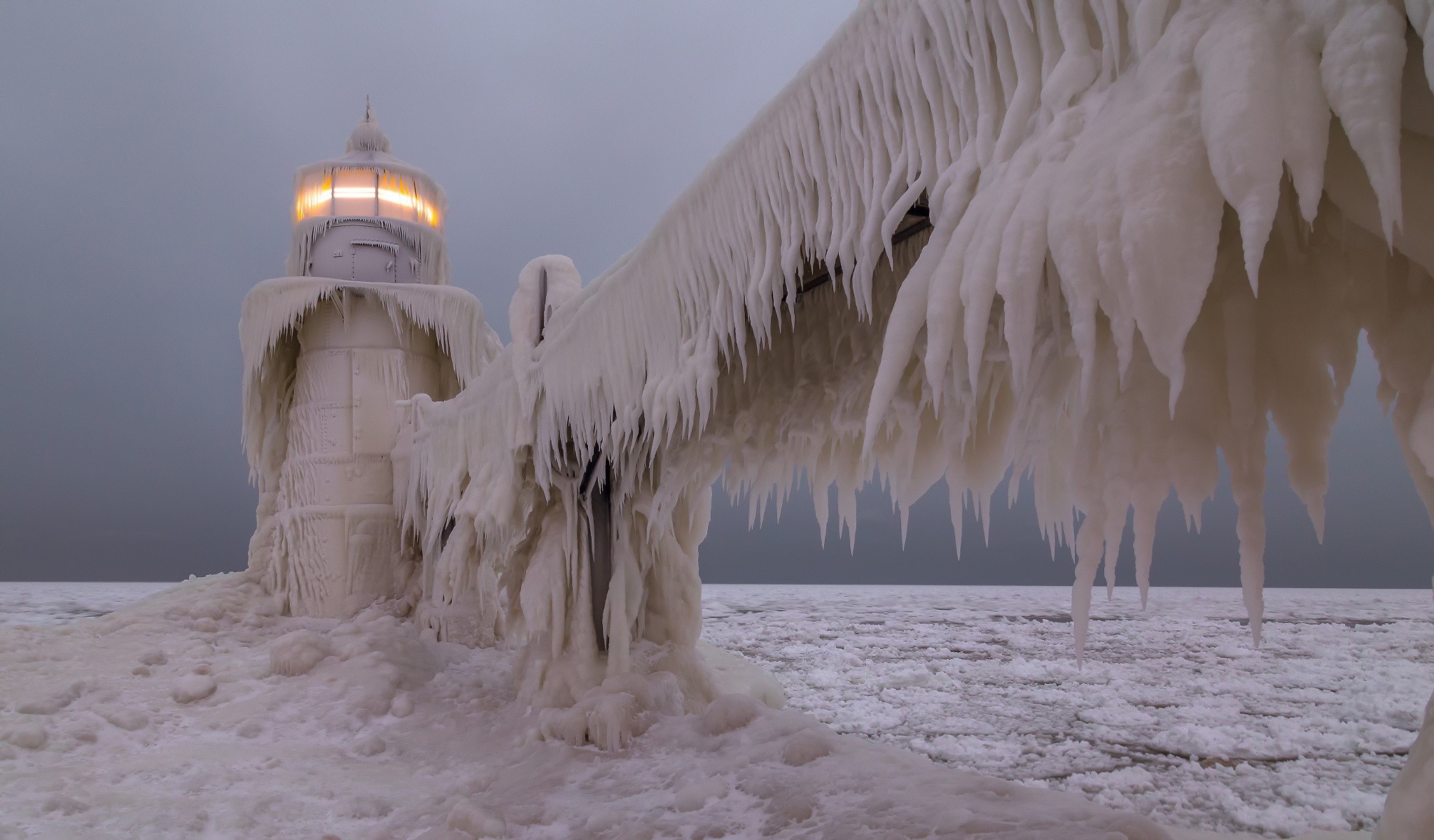 Frozen lighthouse covered in ice with glowing light HD Wallpaper