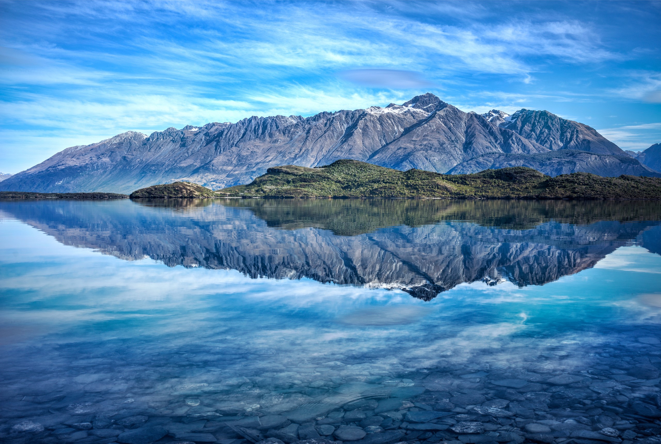 Mountains reflected in a clear lake under a blue sky HD Wallpaper