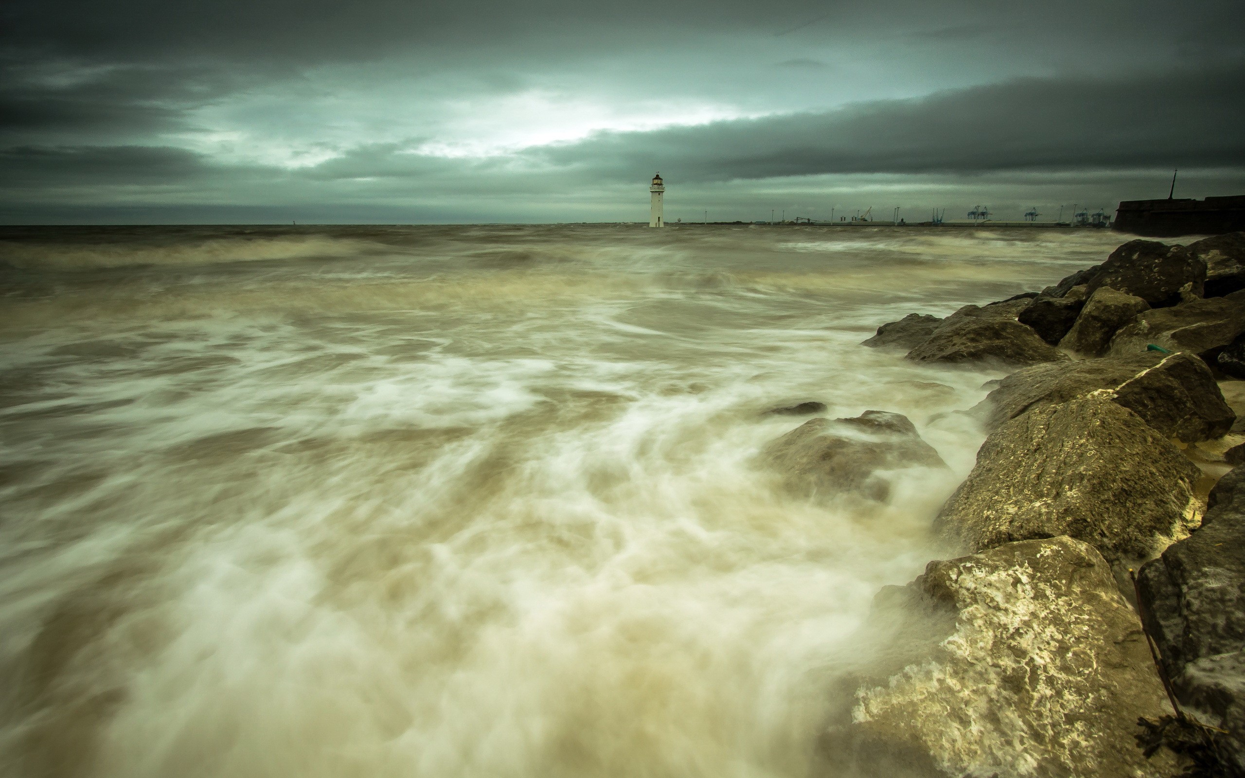 Waves crashing on rocks near a lighthouse HD Wallpaper