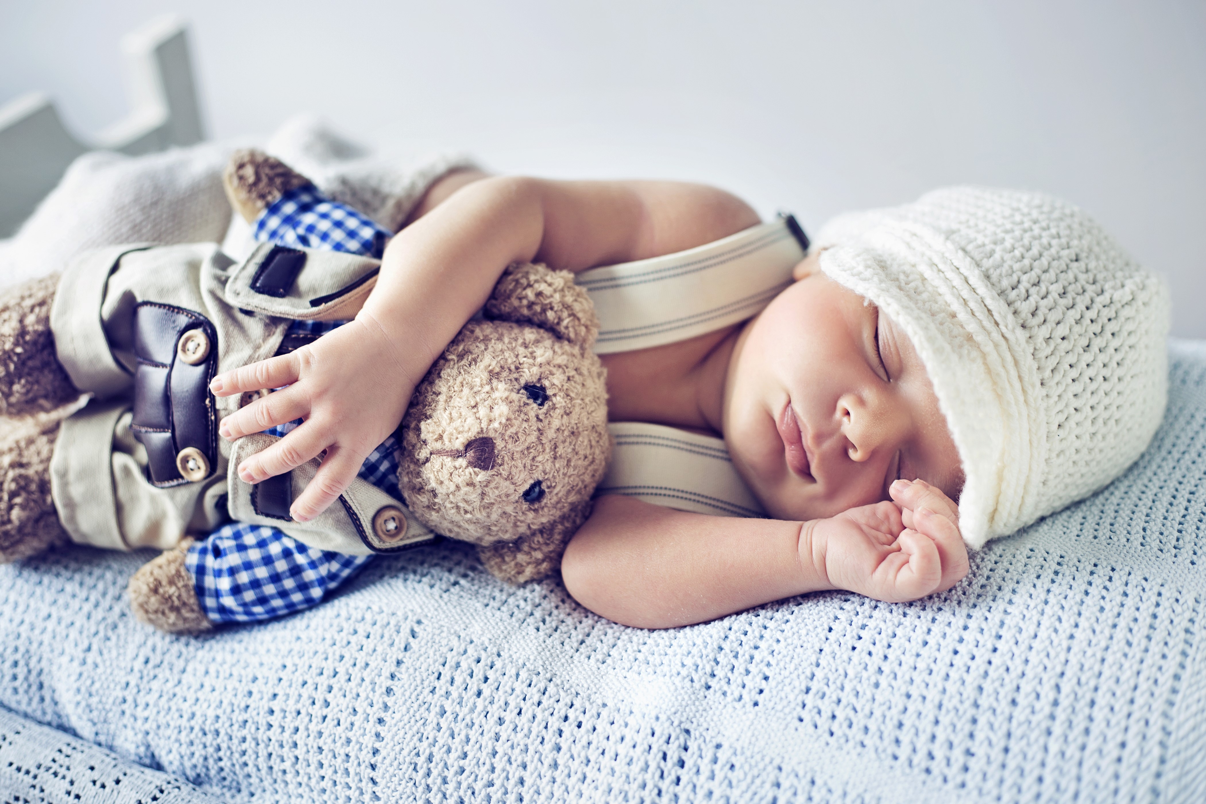 Infant sleeping with teddy bear and winter hat HD Wallpaper