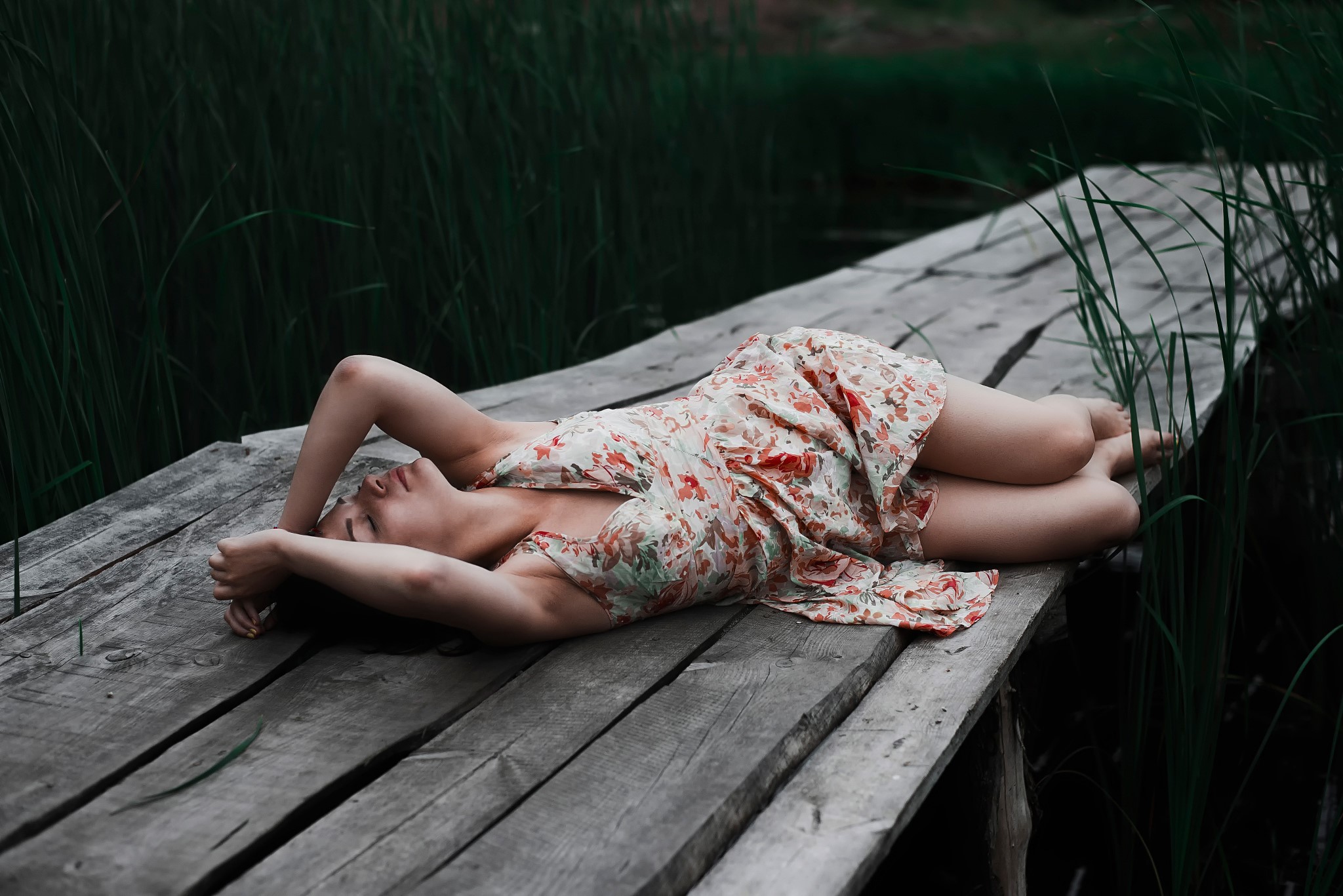 Woman in floral dress sleeping on wooden planks HD Wallpaper