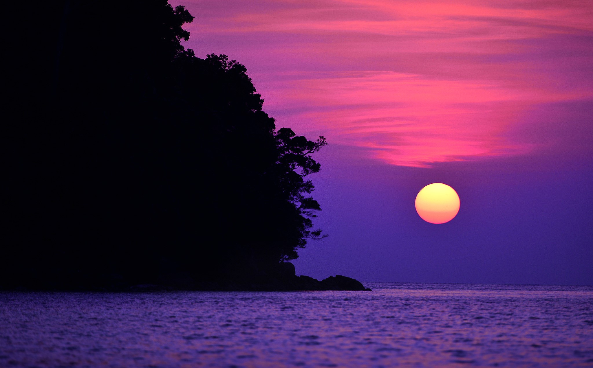 Sunset over the sea with a silhouetted island HD Wallpaper