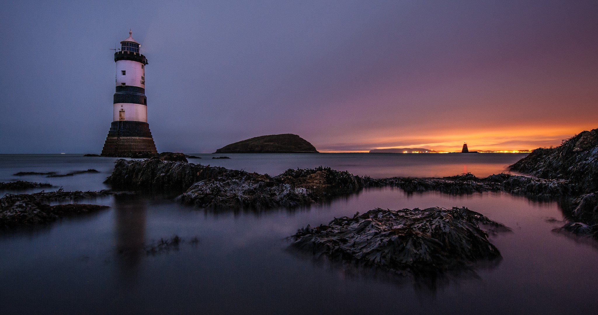 Penmon Lighthouse at dusk with rocky shore HD Wallpaper