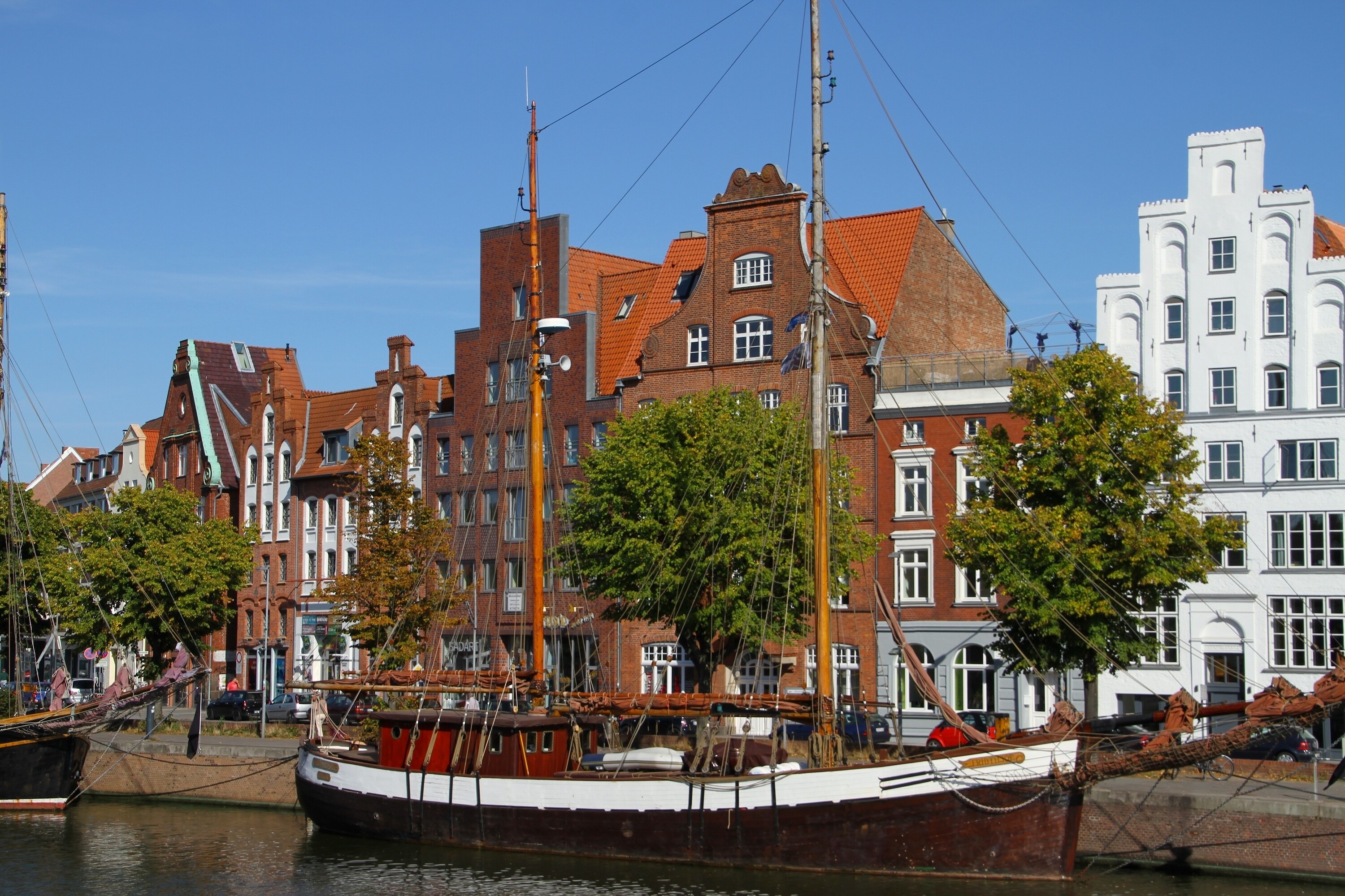 Sailing ships docked in Lubeck, Germany harbor with historic buildings HD Wallpaper