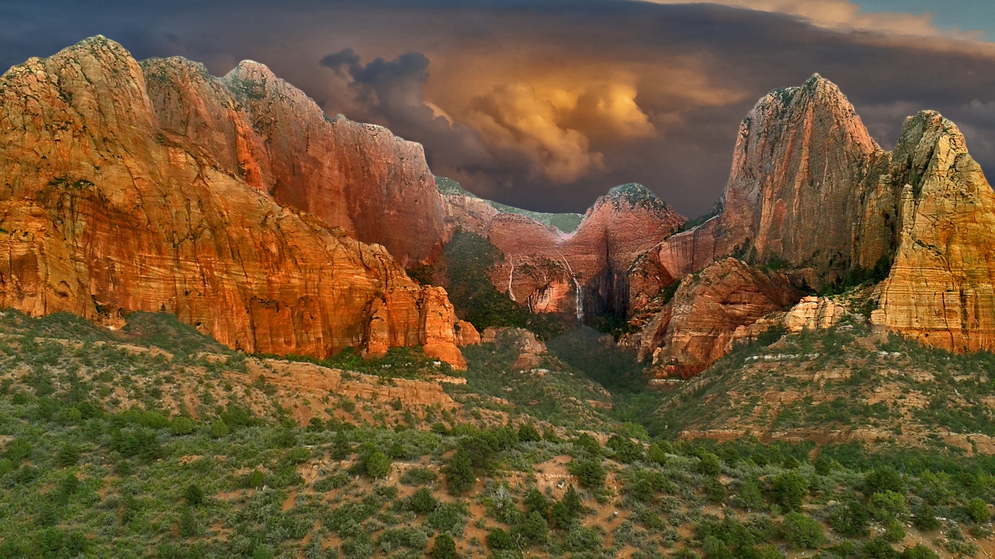 Red rock mountains with waterfalls under a stormy sky HD Wallpaper
