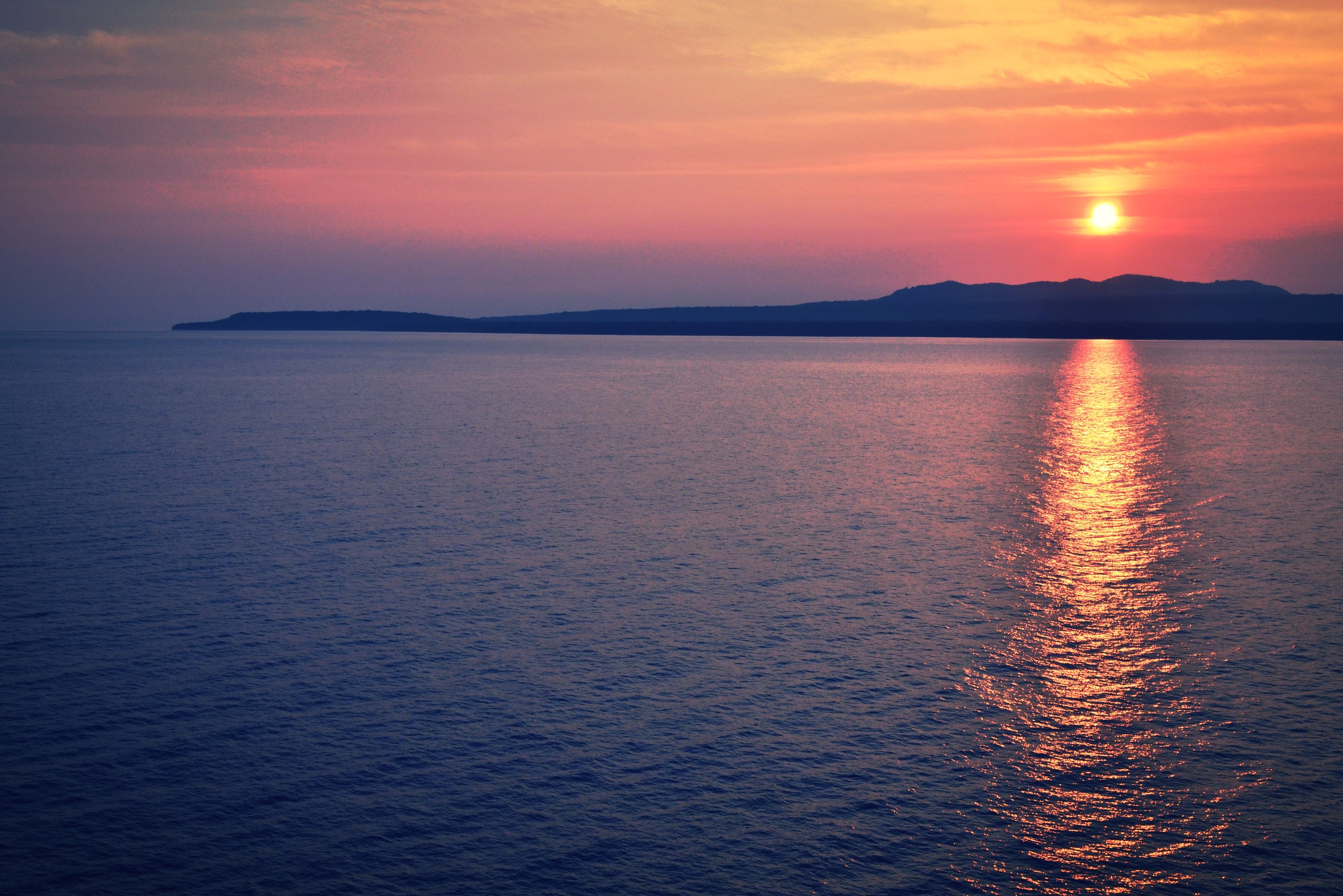 Sunset over the sea with distant hills HD Wallpaper