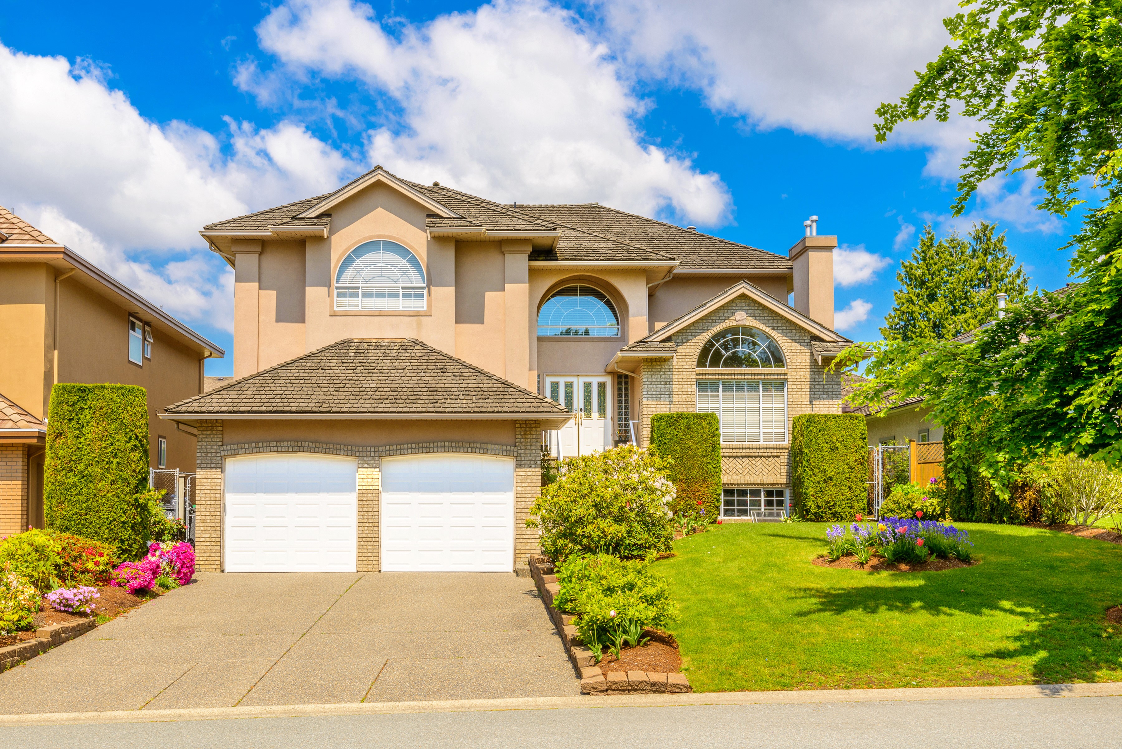 Large beige house with a two-car garage and manicured lawn HD Wallpaper