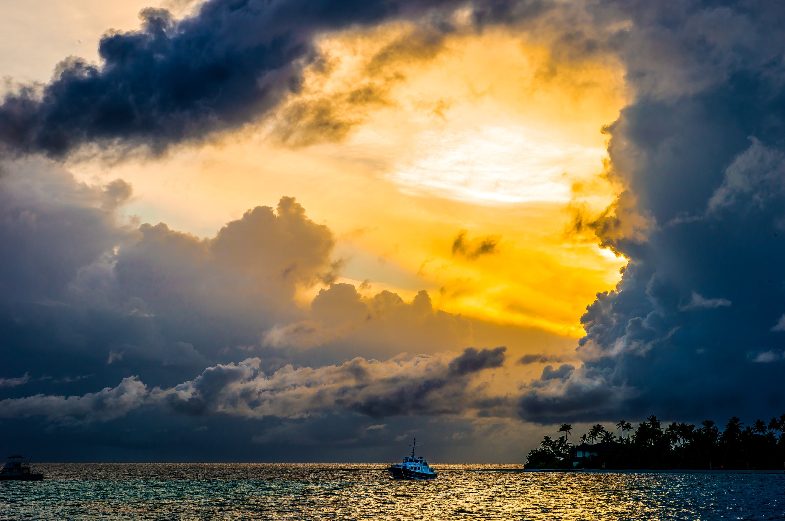 Dramatic sunset over the ocean with a boat and island HD Wallpaper