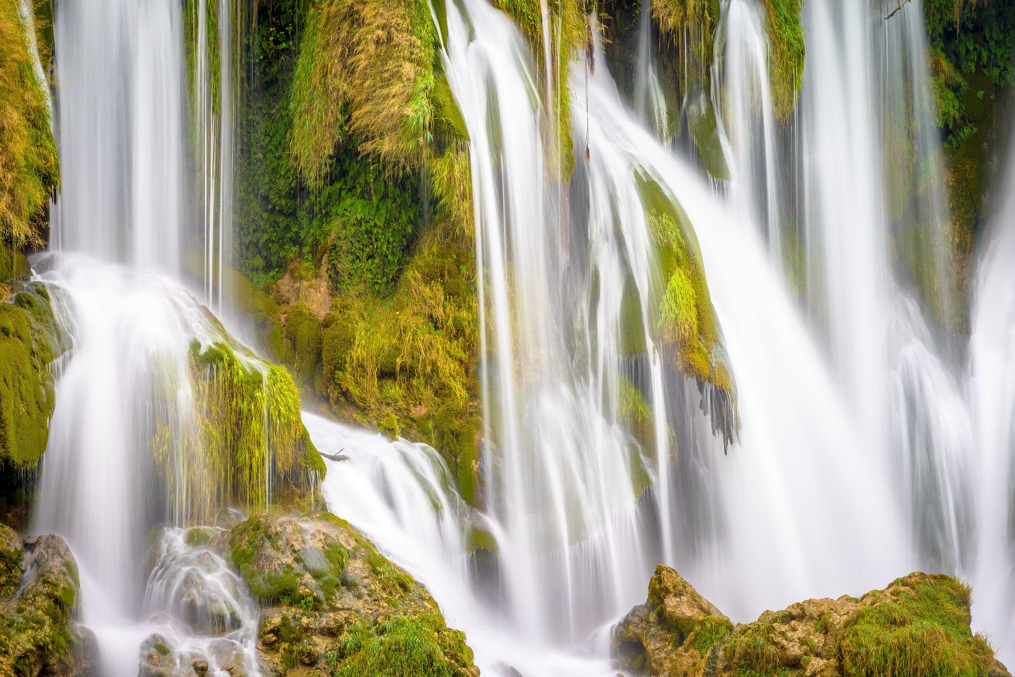 Waterfalls cascading over moss-covered rocks HD Wallpaper