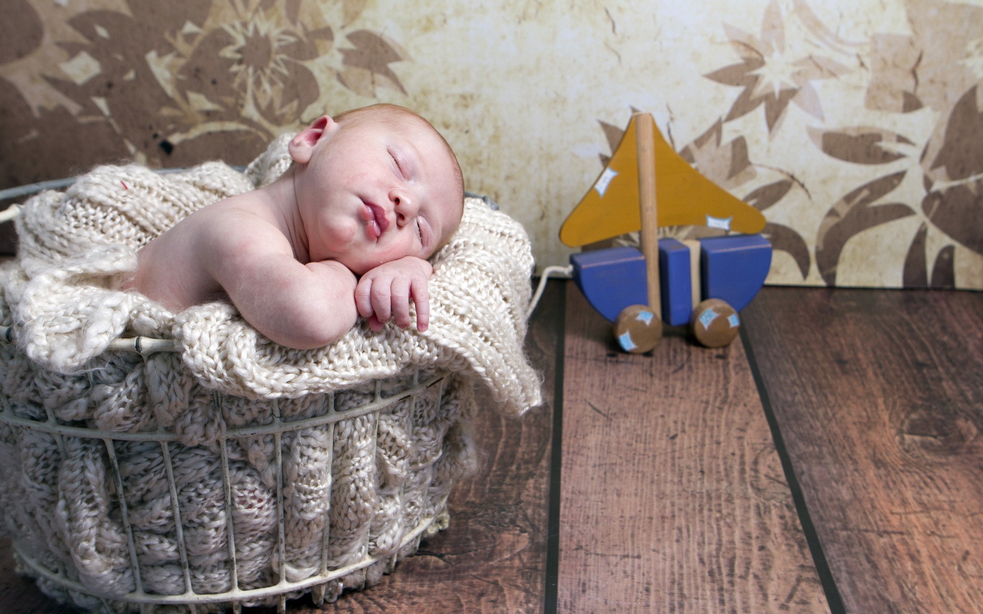 Newborn baby sleeping in a basket with a toy boat HD Wallpaper