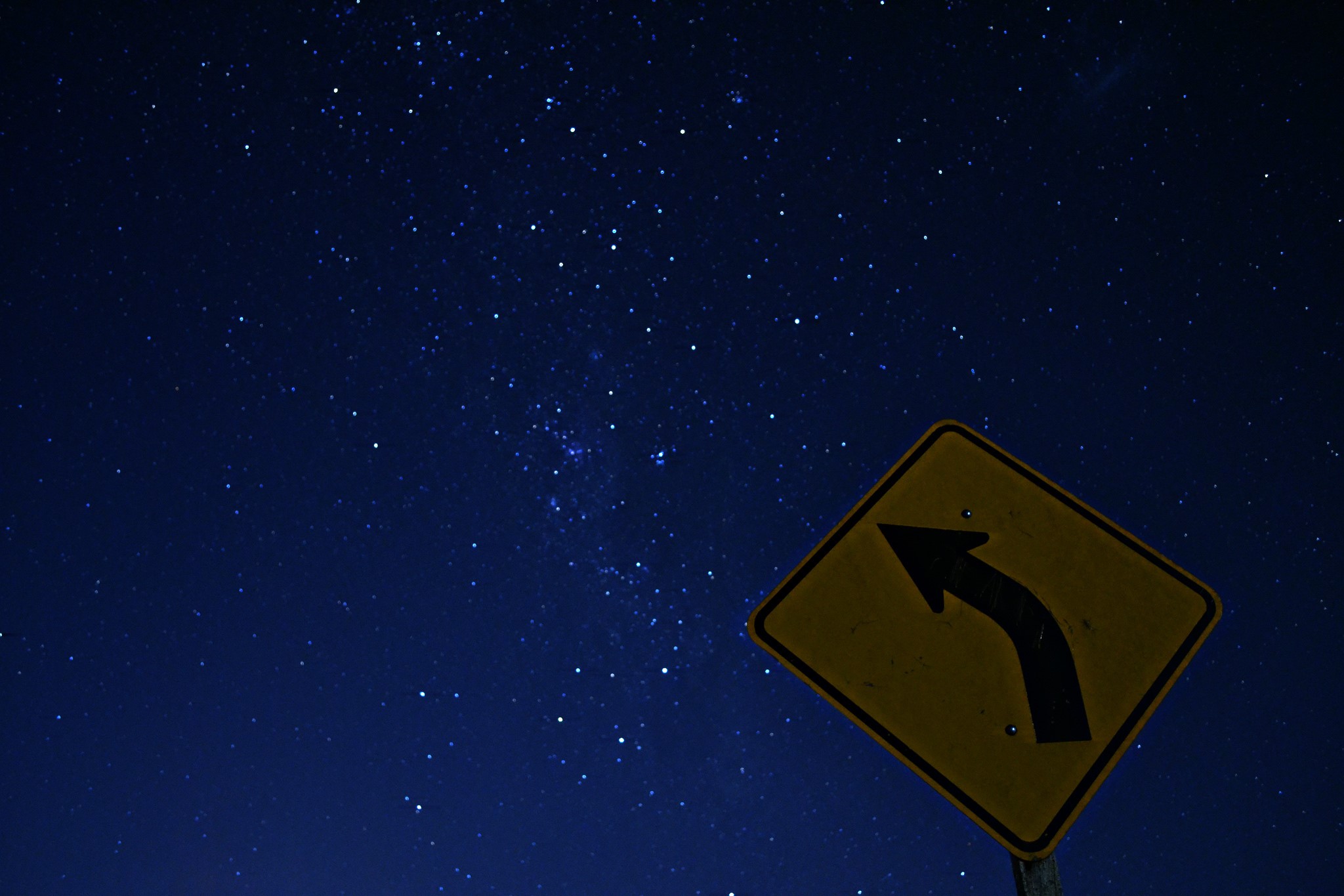Road sign with arrow against starry night sky HD Wallpaper