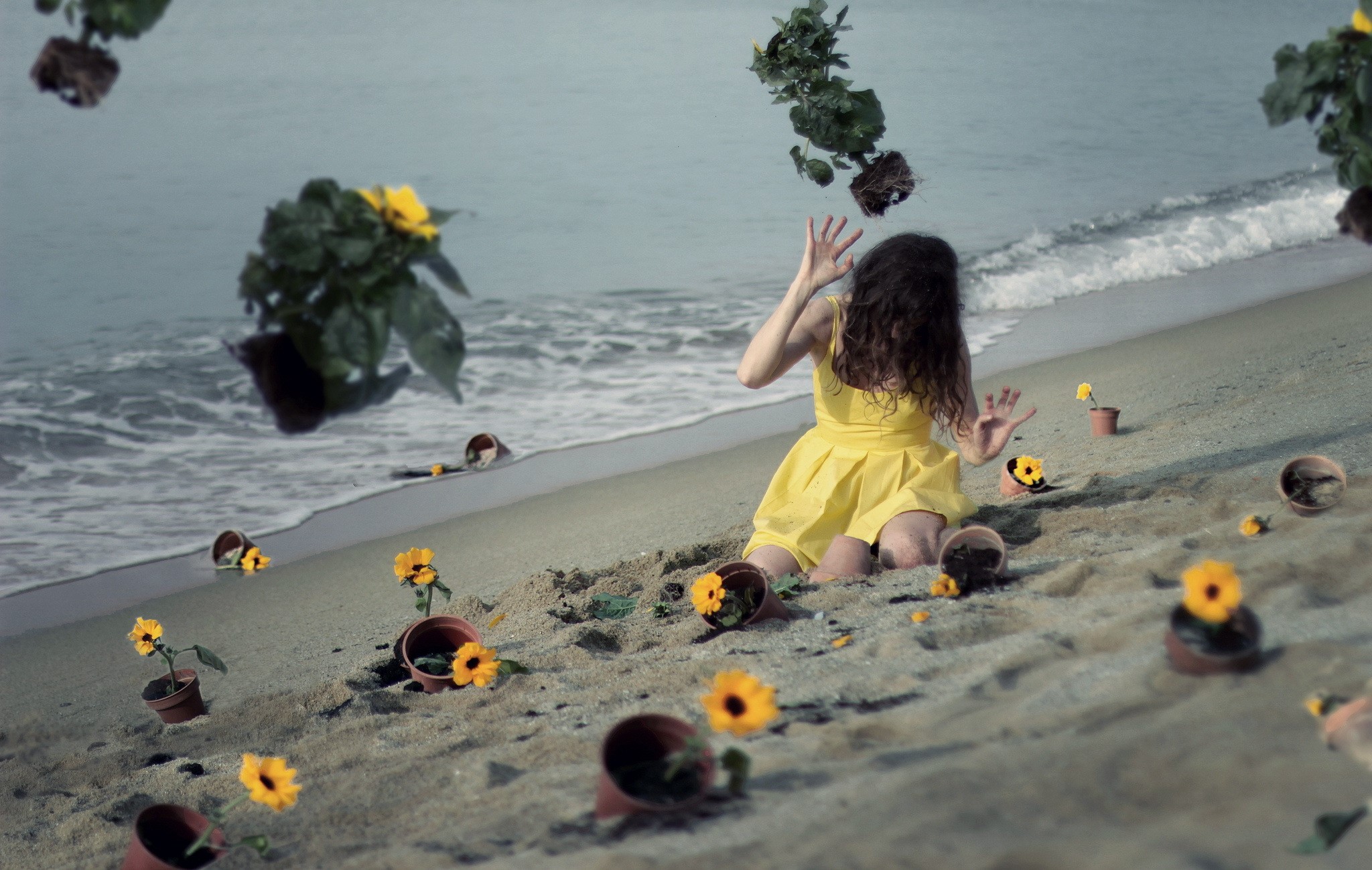 Girl in yellow dress on a beach with scattered potted flowers HD Wallpaper
