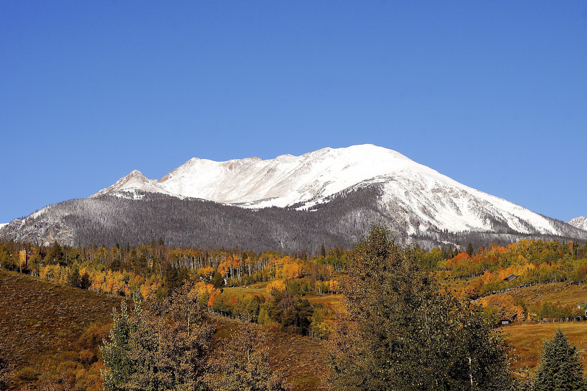 Snow-capped mountain range with autumn forest HD Wallpaper