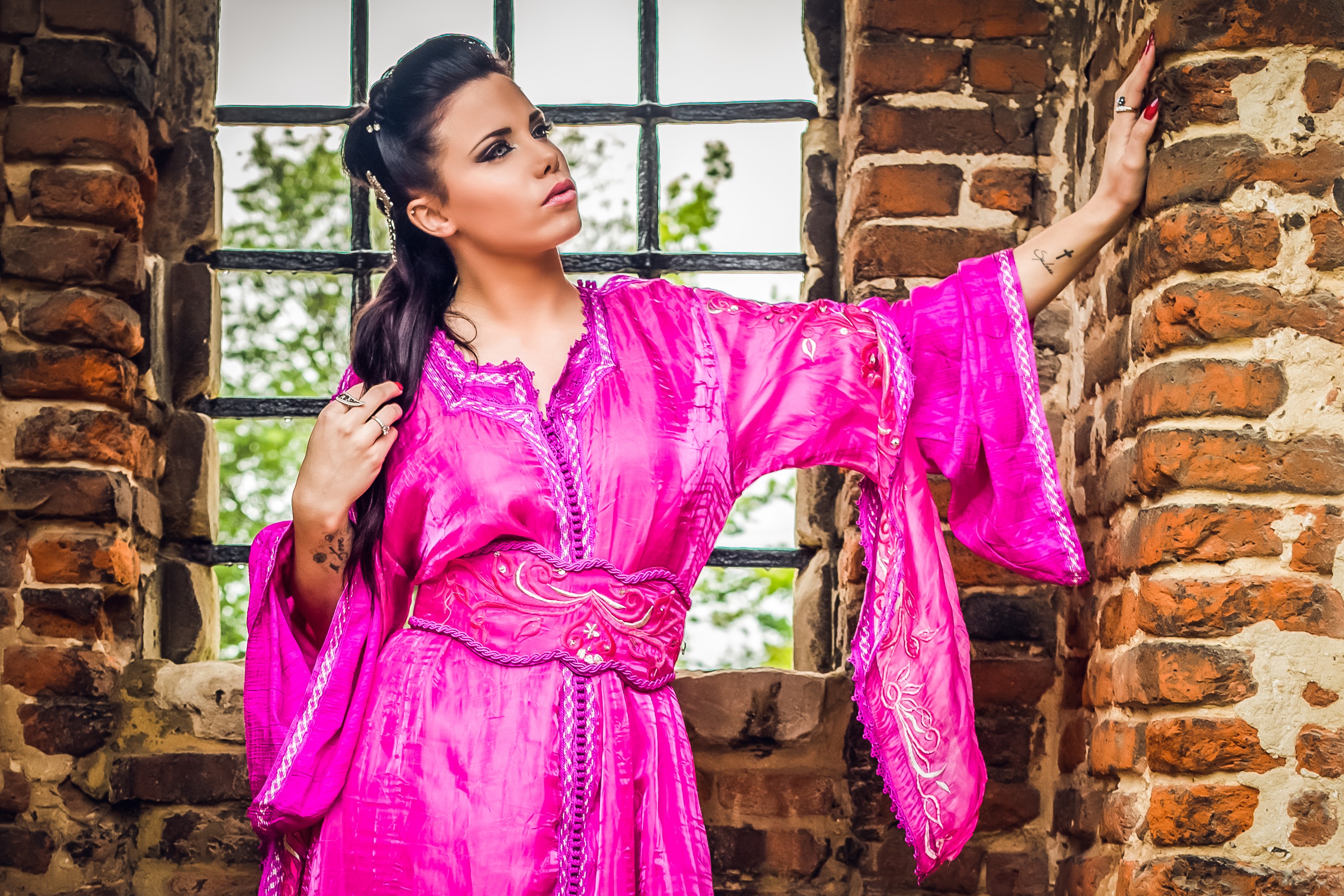 Woman in a pink dress by a brick wall HD Wallpaper