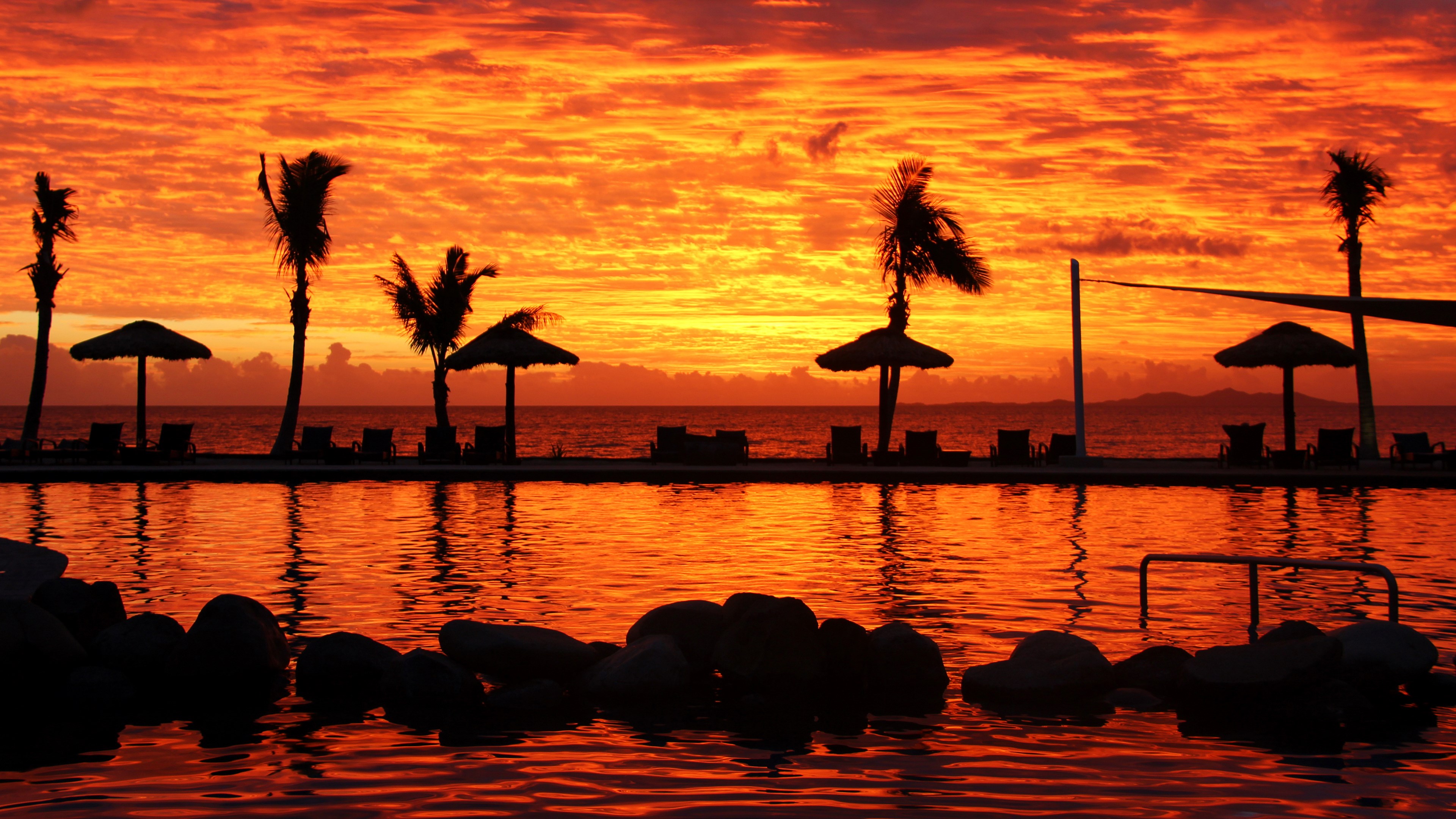 Tropical beach sunset with palm trees and swimming pool HD Wallpaper