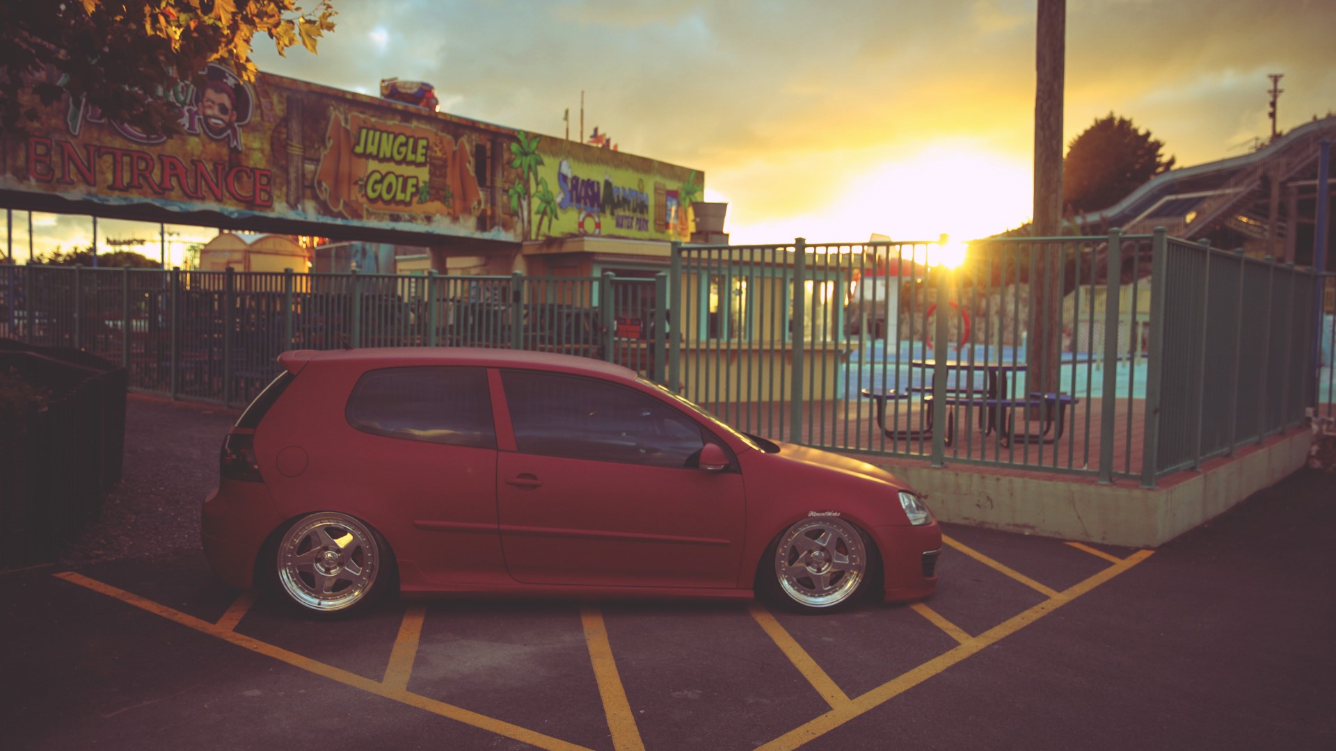 Red Volkswagen Golf parked at Jungle Golf HD Wallpaper