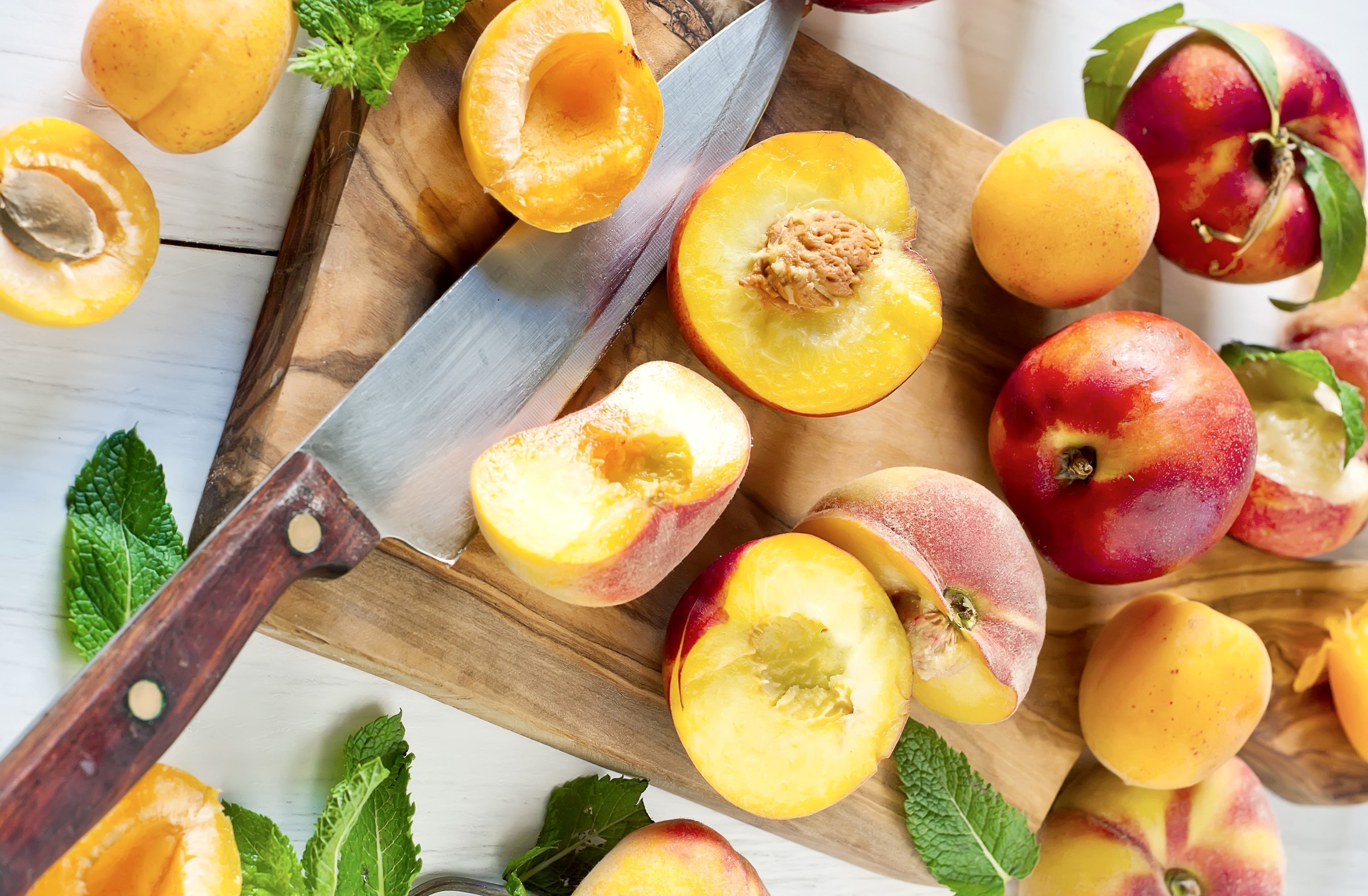 Peaches and apricots on a cutting board with a knife HD Wallpaper