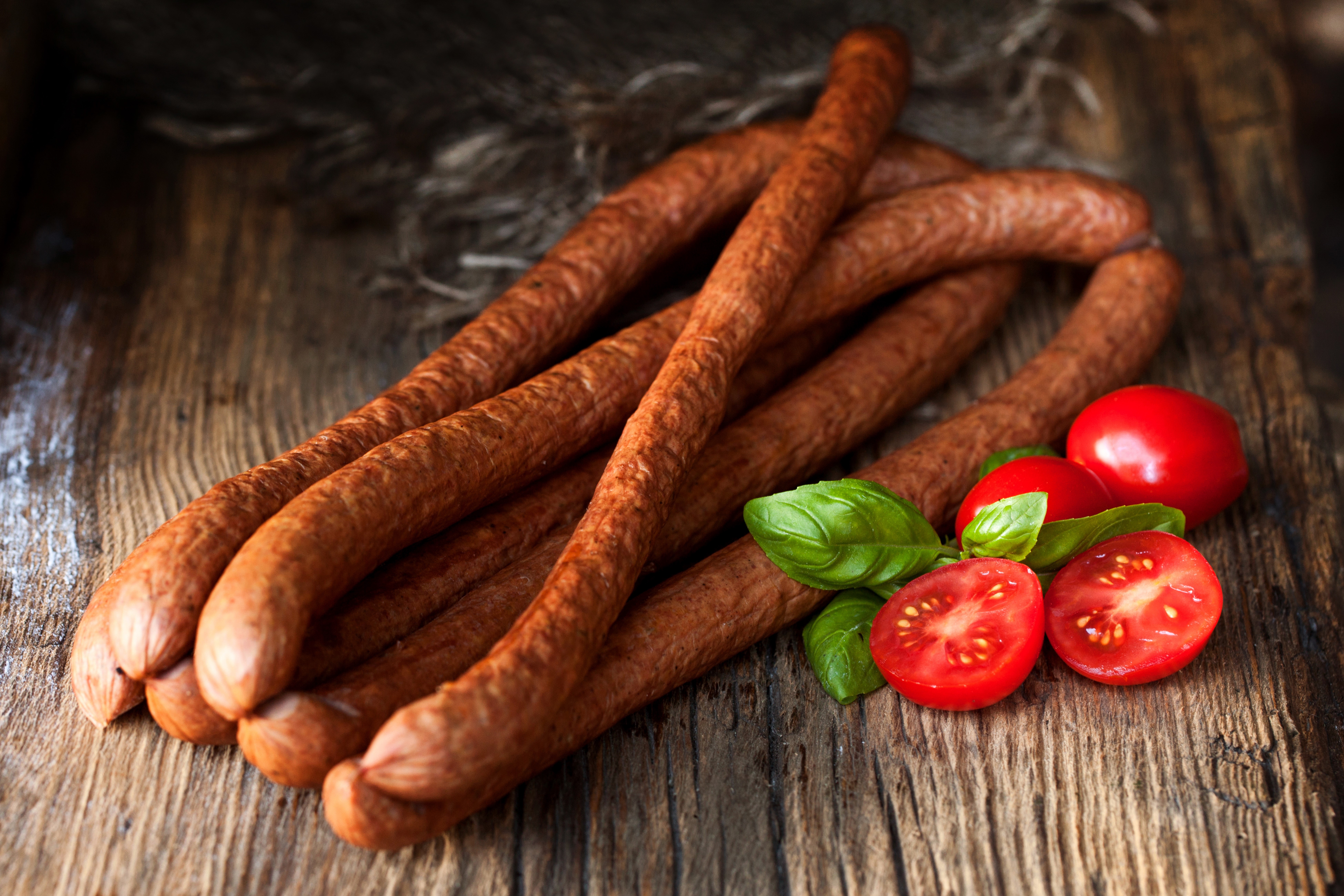 Sausages with tomatoes and basil on a wooden table HD Wallpaper