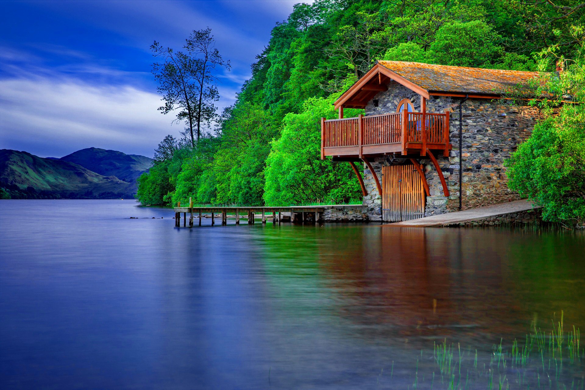 Stone boathouse on a lake with a wooden dock HD Wallpaper