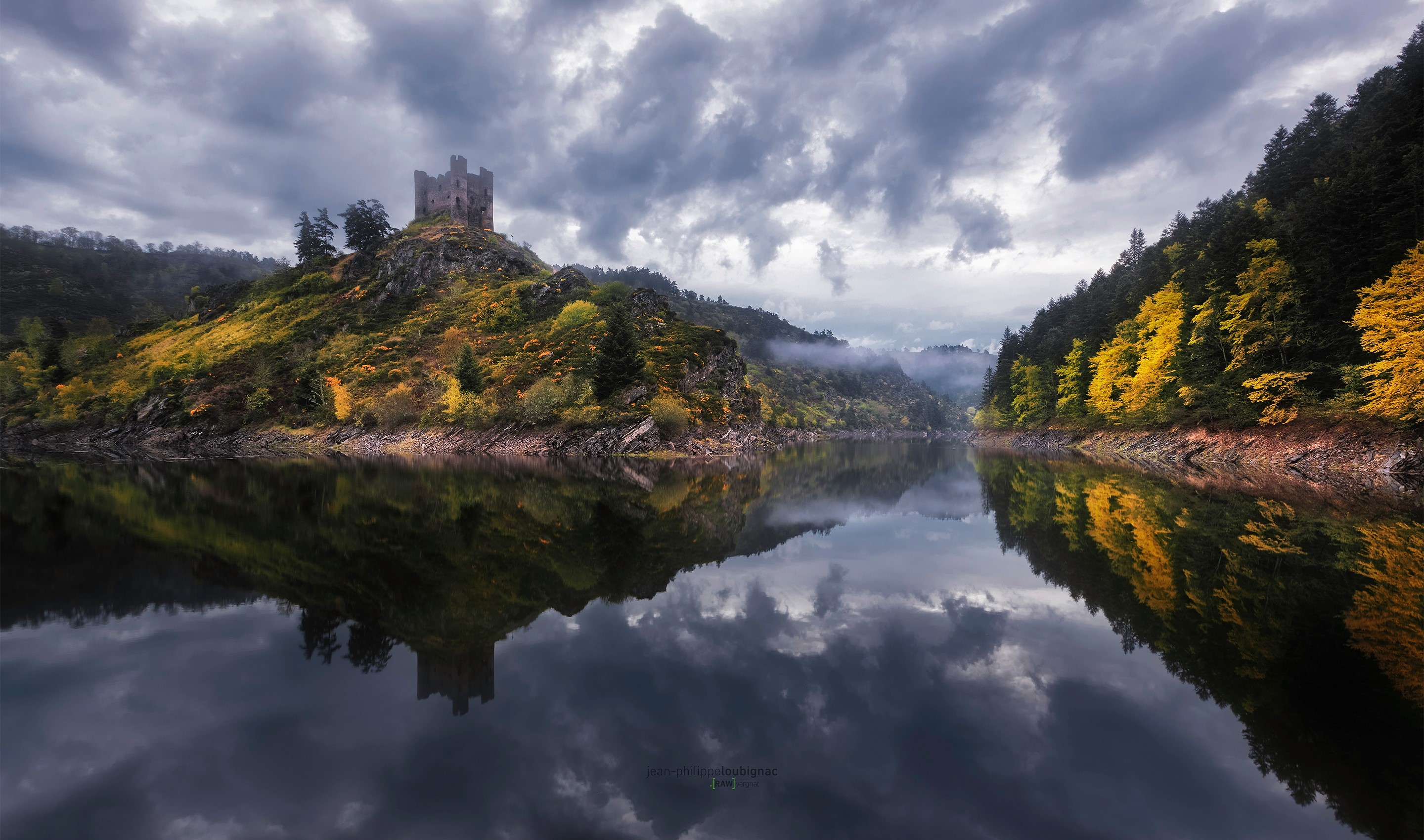 Castle on a hill reflected in a lake with autumn trees HD Wallpaper