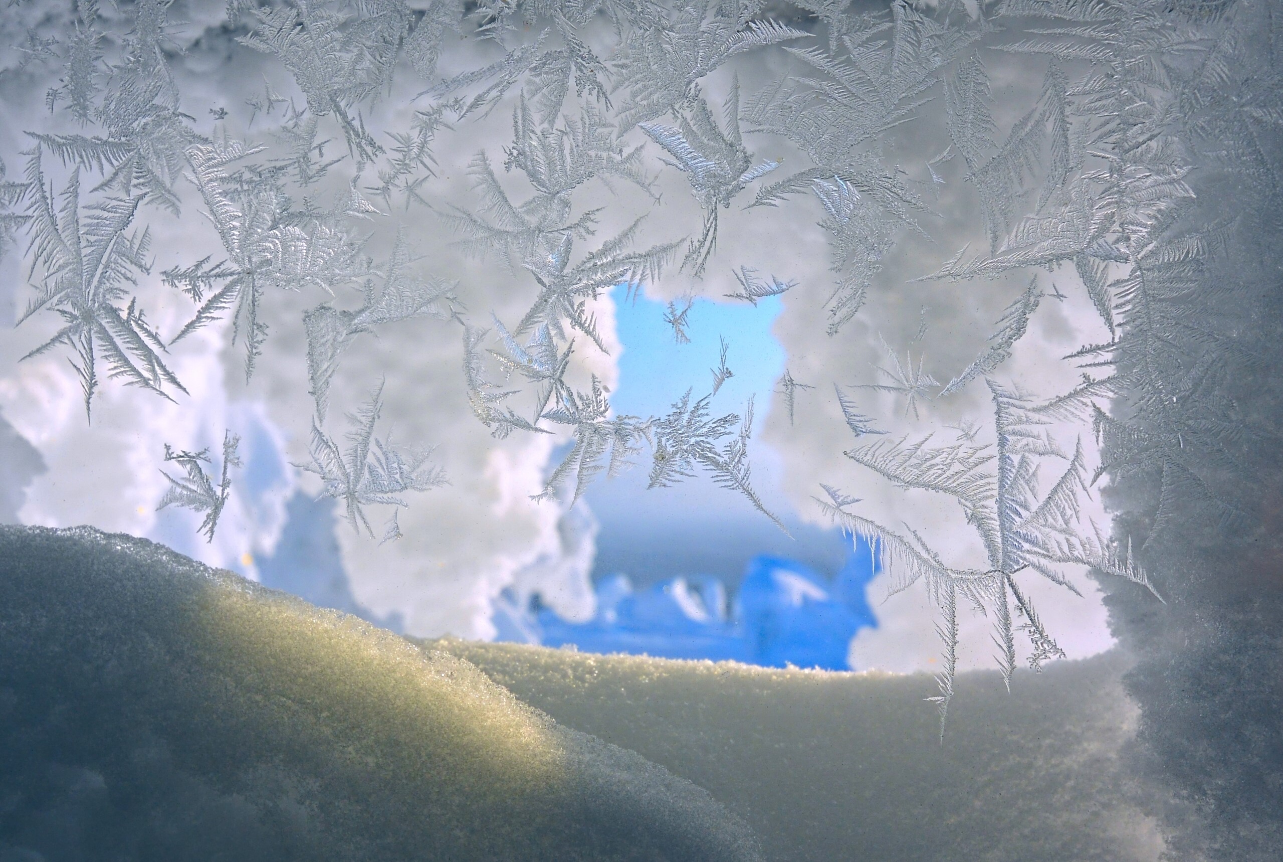 Frost patterns on a window with snow and sky HD Wallpaper