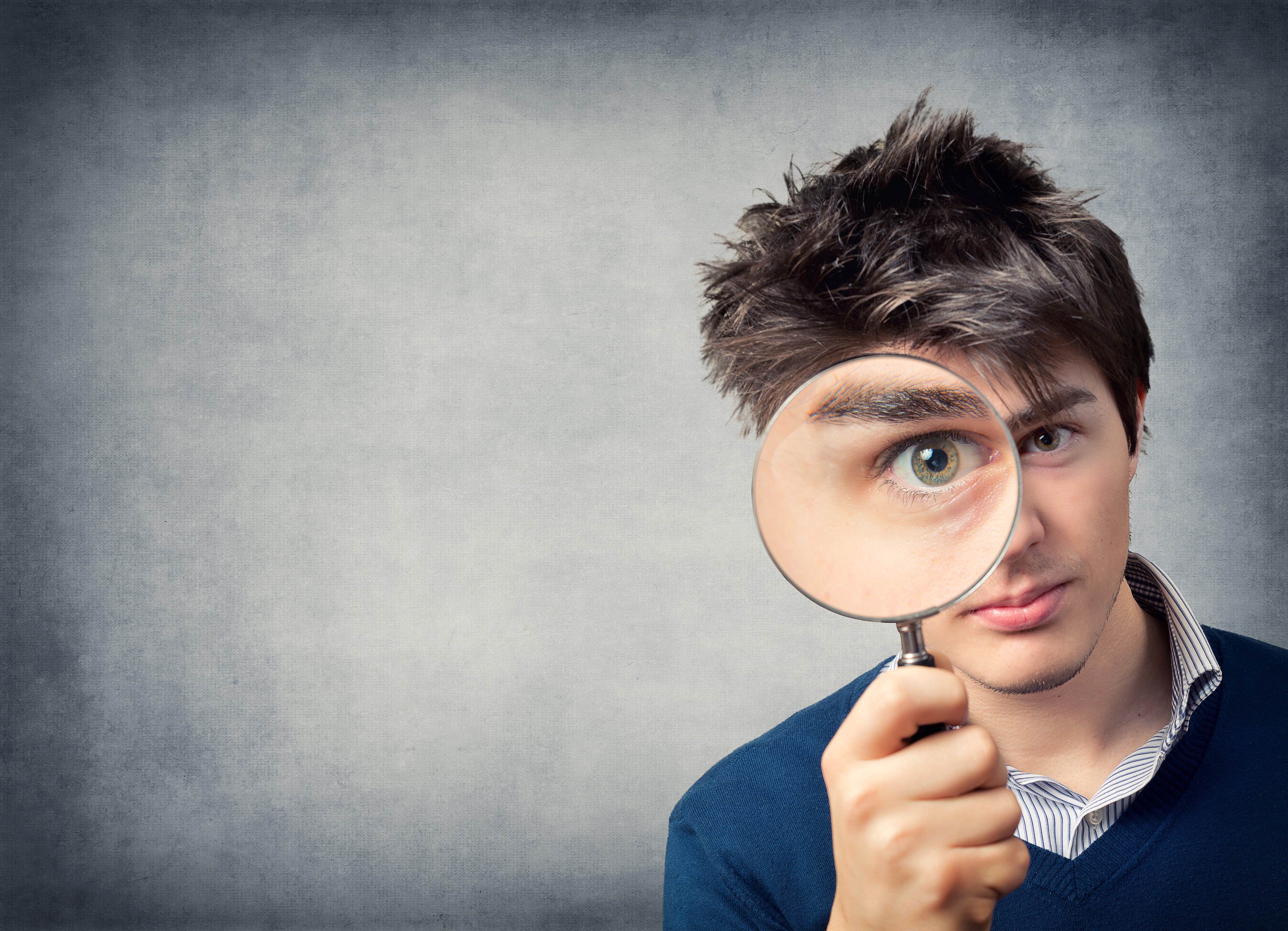 Man looking through a magnifying glass HD Wallpaper