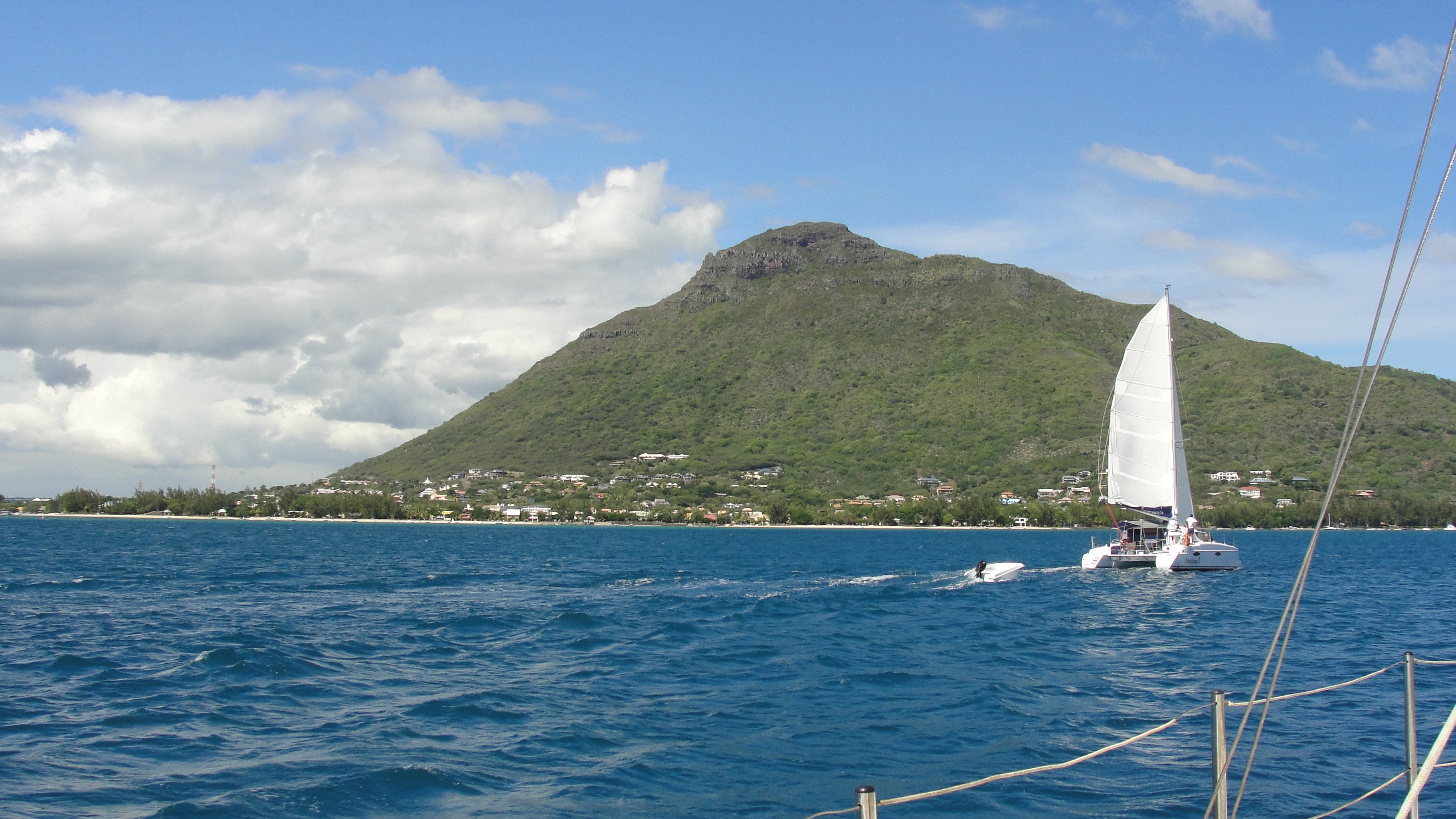 Catamaran sailing near Mauritius with green mountain in background HD Wallpaper