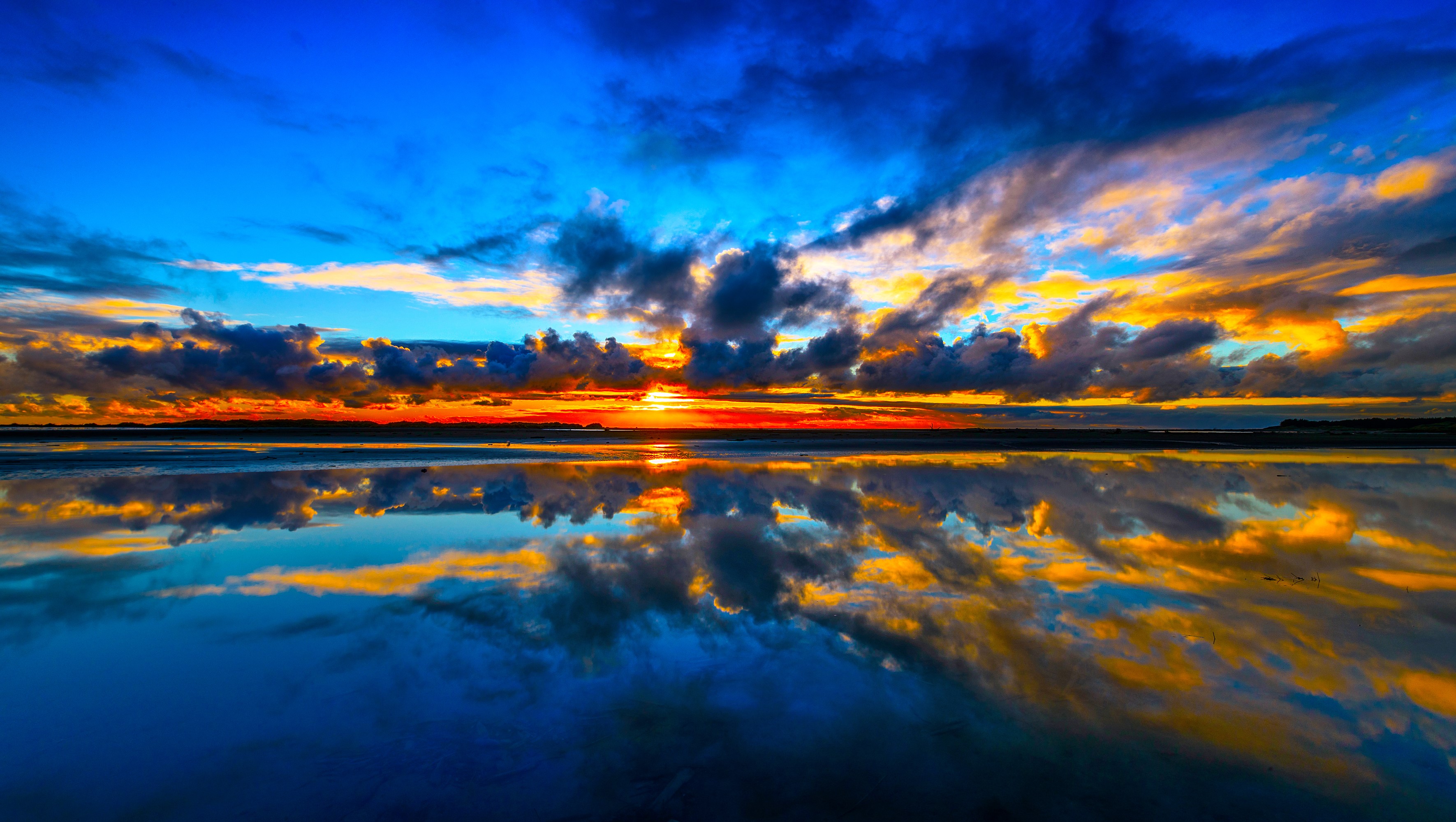 Sunset over a calm body of water with colorful clouds HD Wallpaper