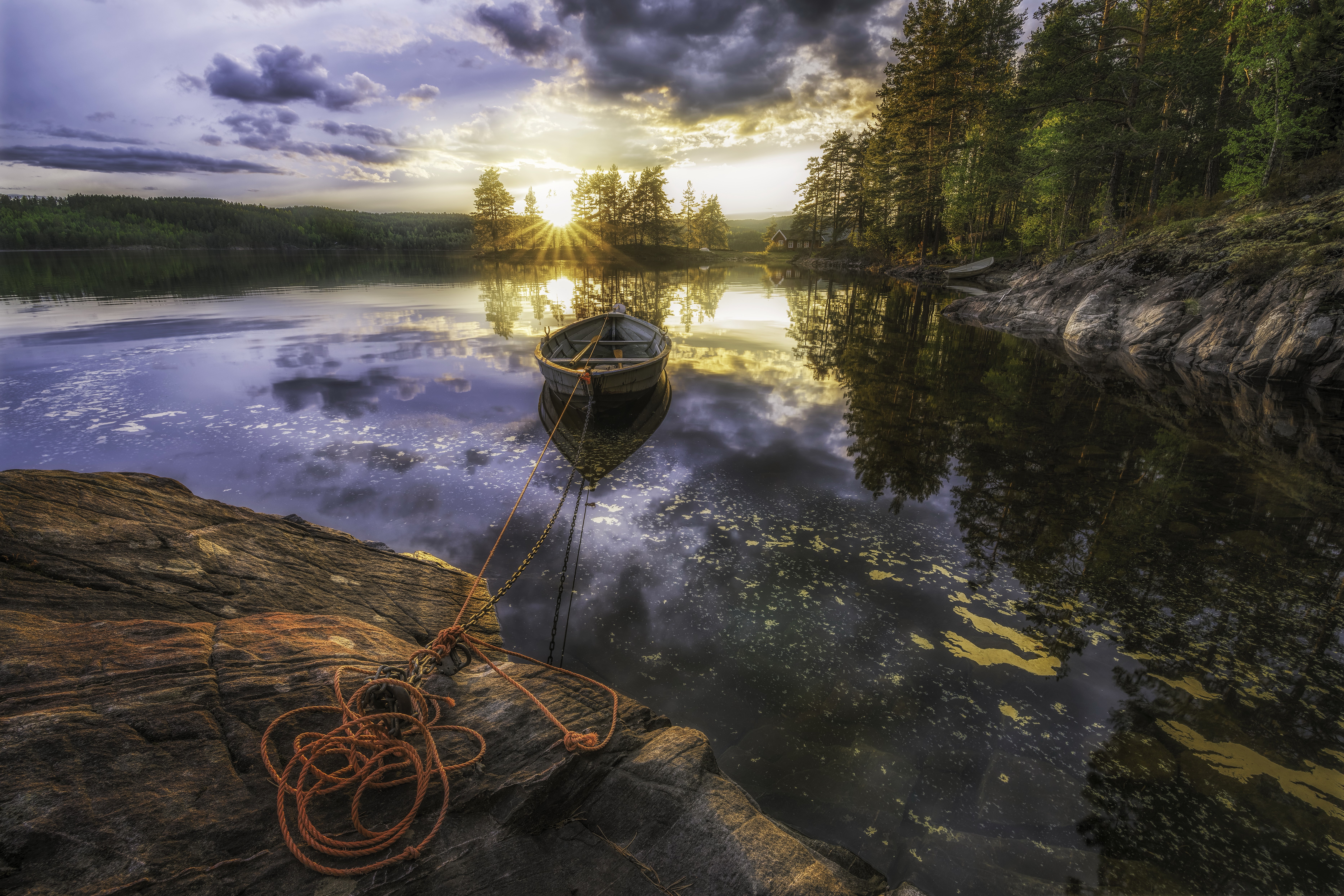 Boat on a lake at sunset with rocky shore HD Wallpaper